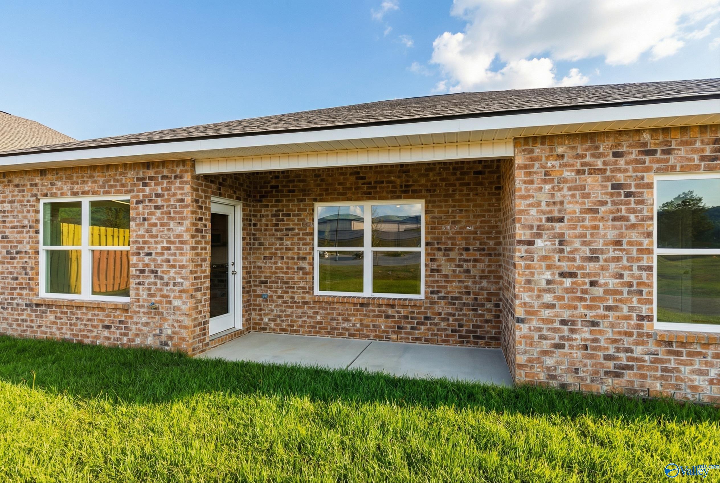 Brick single-story home exterior with covered entry porch, large windows, and lush green lawn in Jaguar Hills, Huntsville, Alabama - Davidson Homes Asheville C