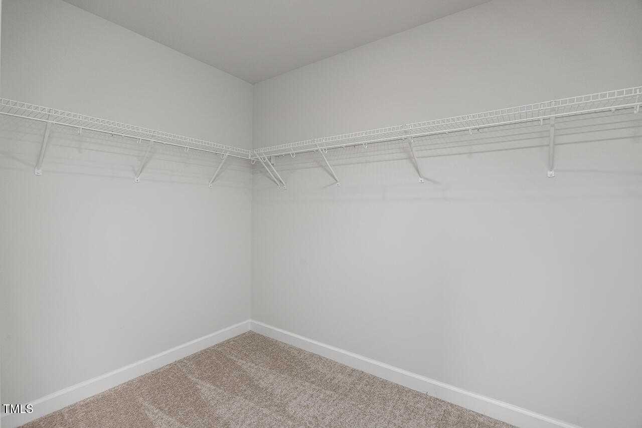 Spacious walk-in closet with white walls, wire shelving, and beige carpet in Davidson Homes The Graham 3-bedroom, Fuquay-Varina, NC