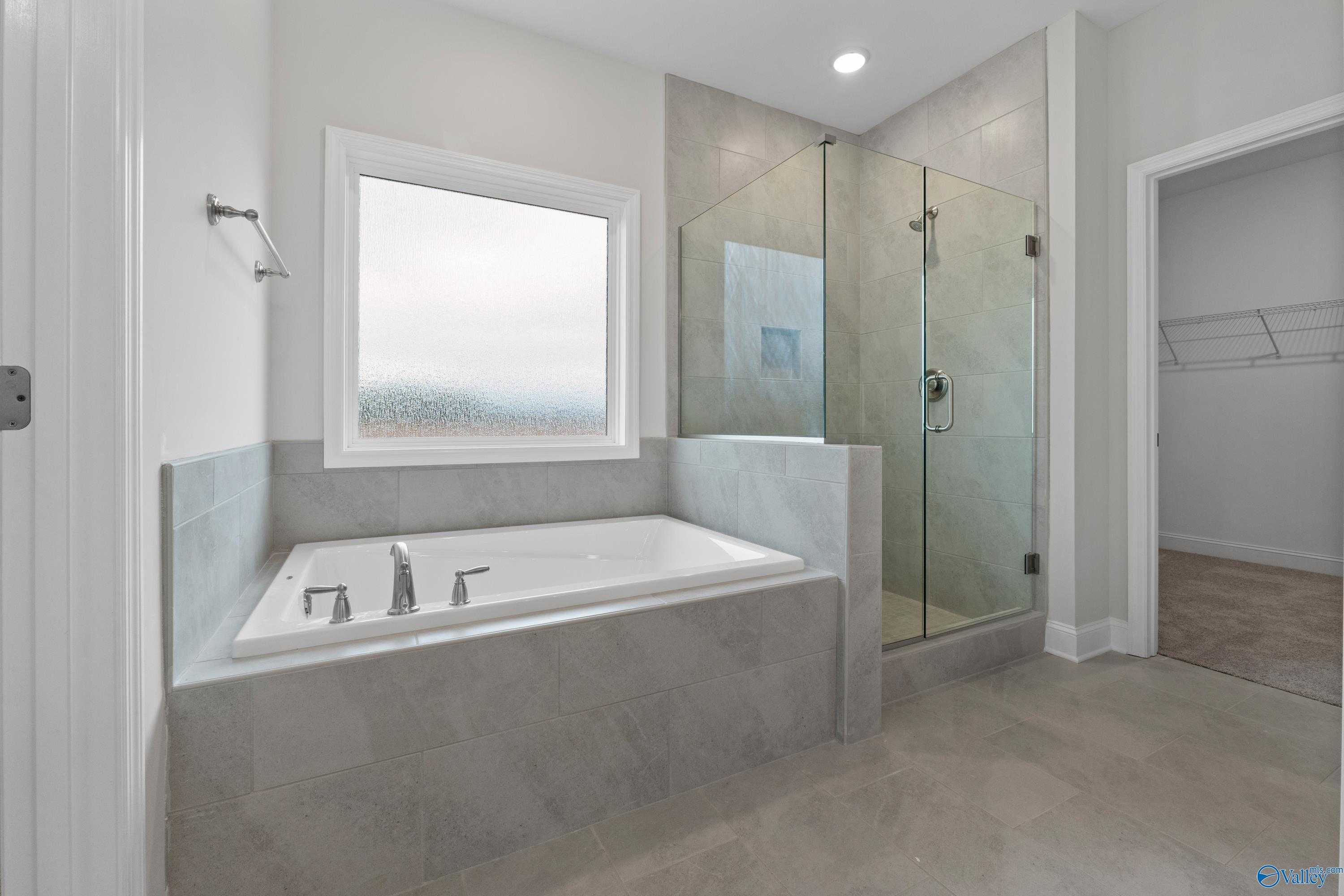 Luxurious master bathroom with freestanding tub, glass walk-in shower, and large window in Davidson Homes The Rockford B, Toney, Alabama