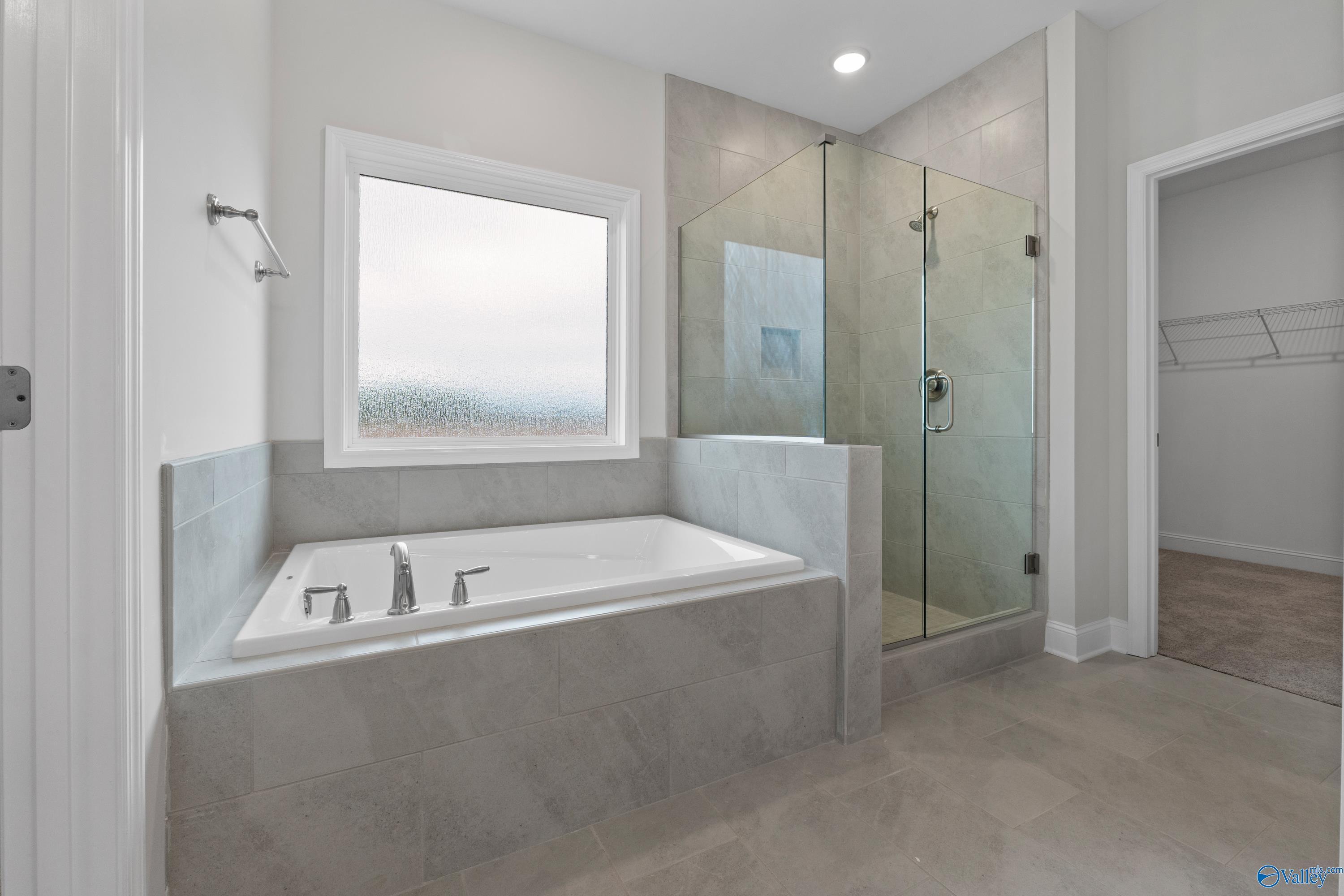 Elegant master bathroom with freestanding soaking tub, glass walk-in shower, and large window in Davidson Homes The Rockford B, Toney, Alabama