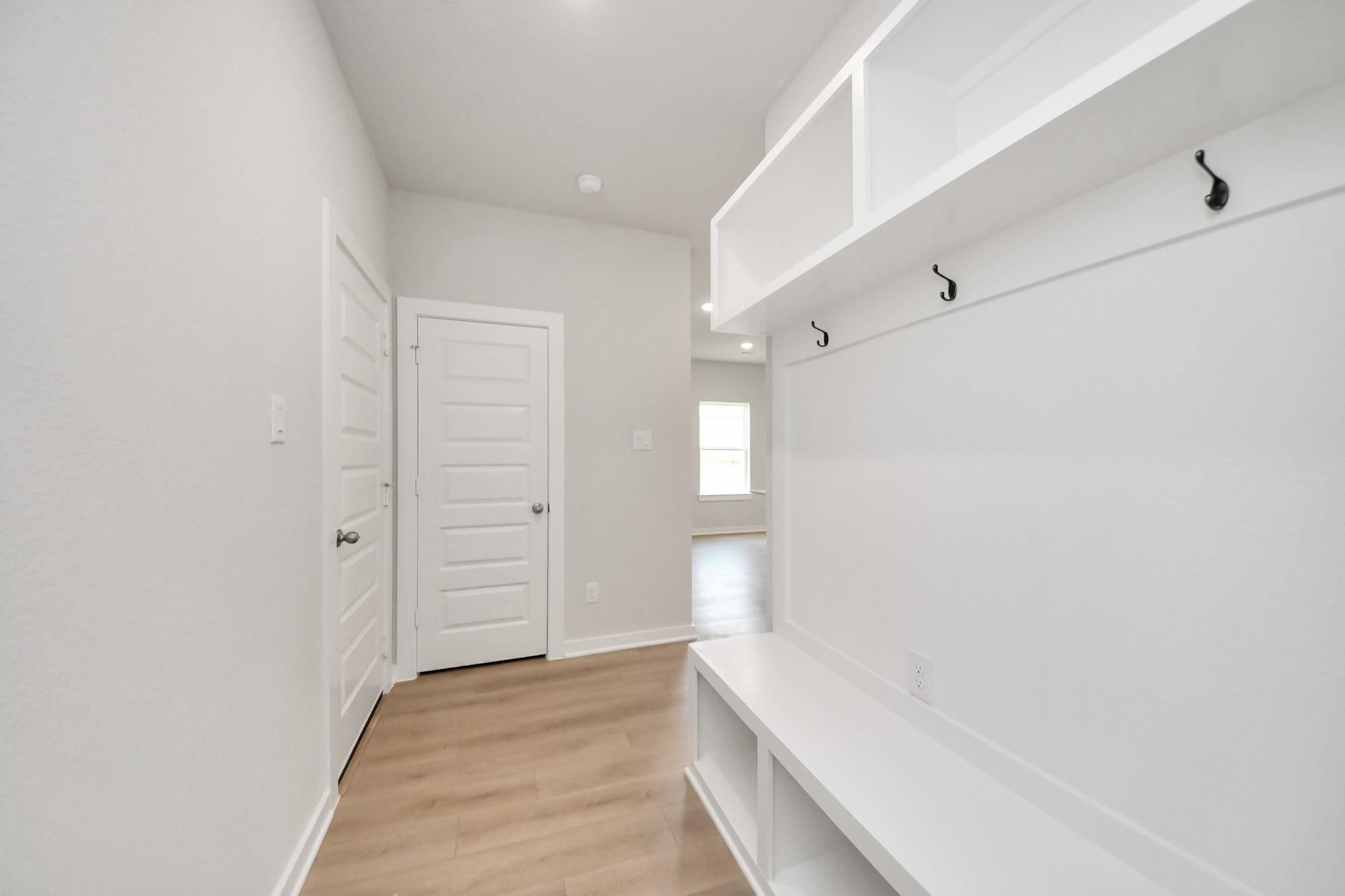 Modern mudroom entry with built-in storage bench and coat hooks in The Blanco E floor plan at Caney Creek Place, Conroe.