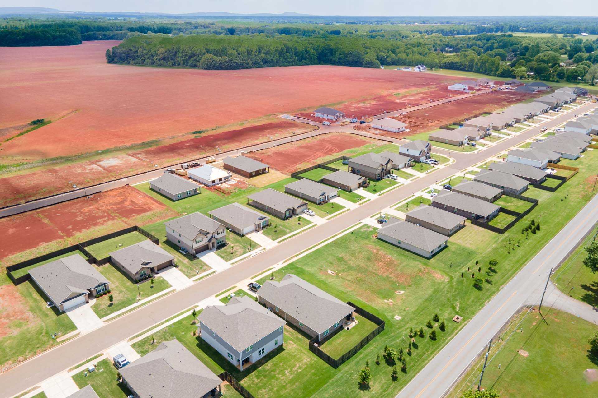 Aerial view of new homes under construction in Clearview Hazel Green Alabama by Davidson Homes amid red dirt fields and woods