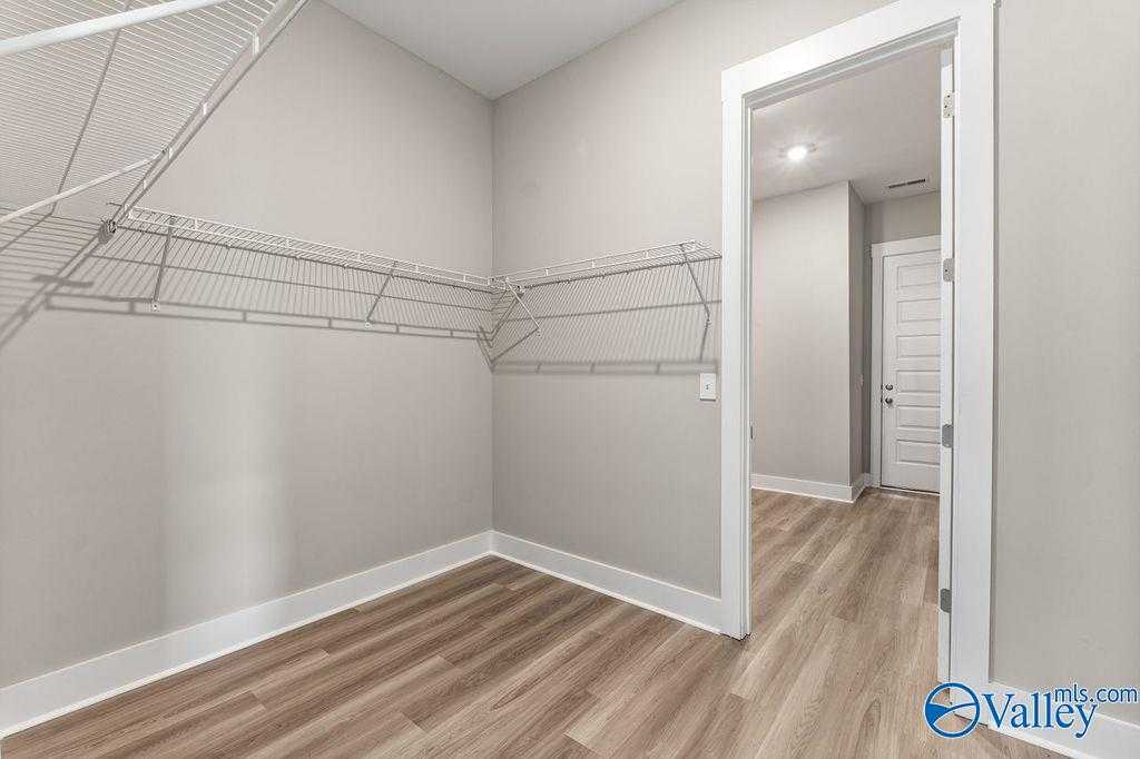 Spacious walk-in closet with wire shelving, gray walls, and laminate wood floors in Evermore Homes The Oxford, Owens Cross Roads, Alabama