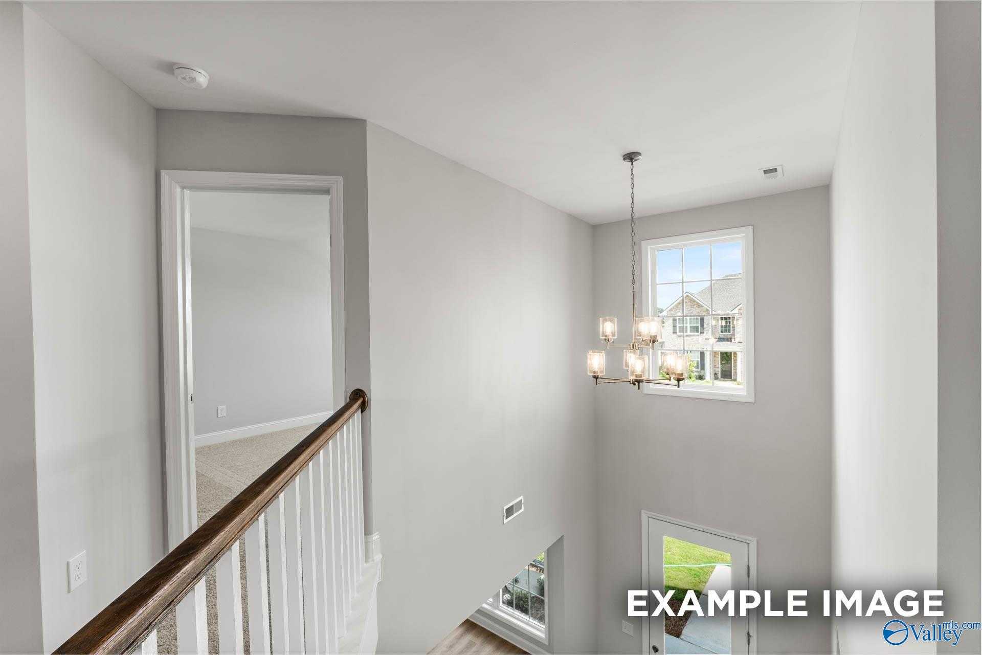 Two-story foyer with wooden balustrade, chandelier, and window view in Davidson Homes The Madison A, Creekside, Harvest, Alabama