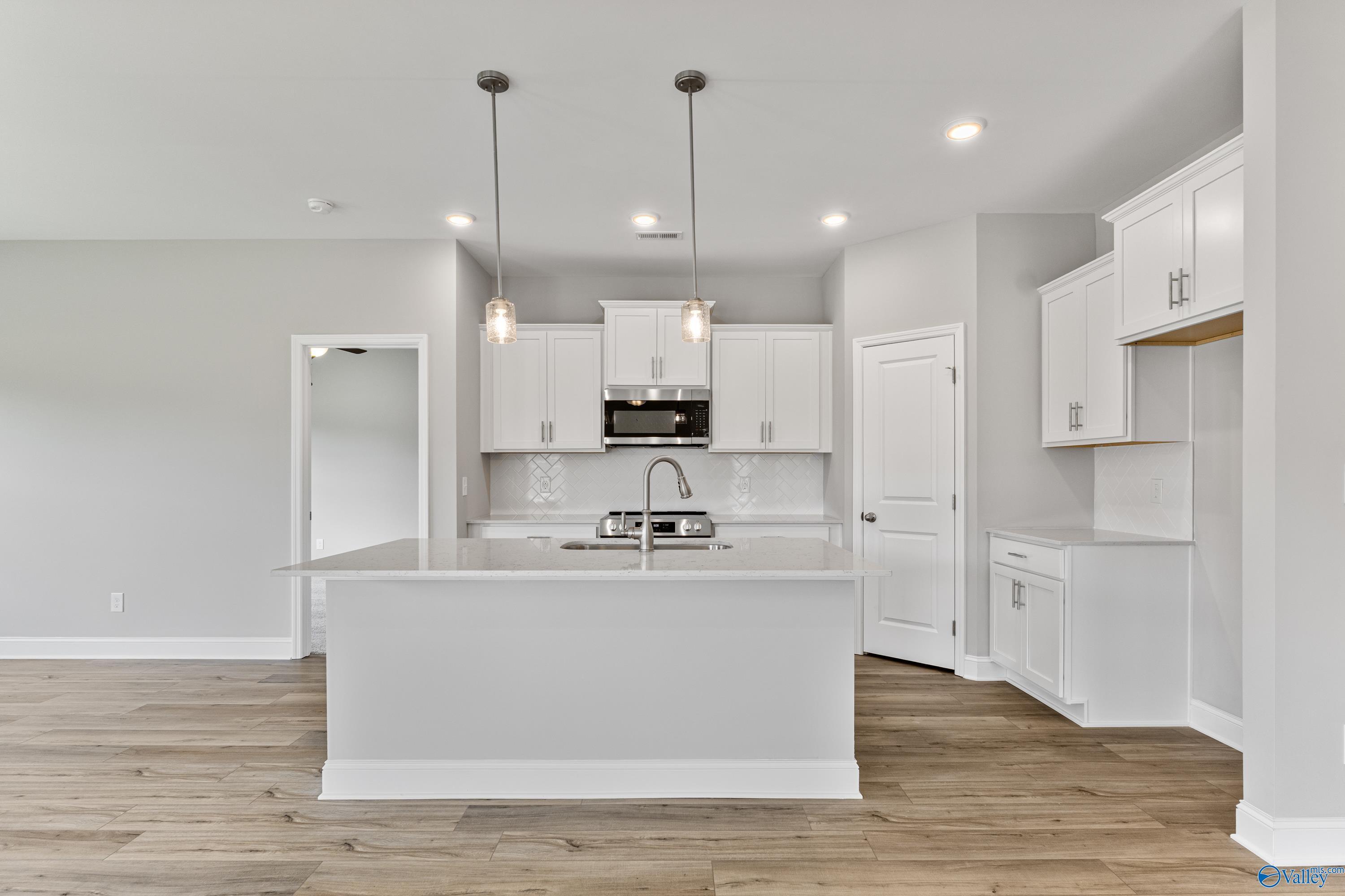Bright modern kitchen with white cabinets, quartz island, stainless appliances in The Franklin C by Davidson Homes, Huntsville AL