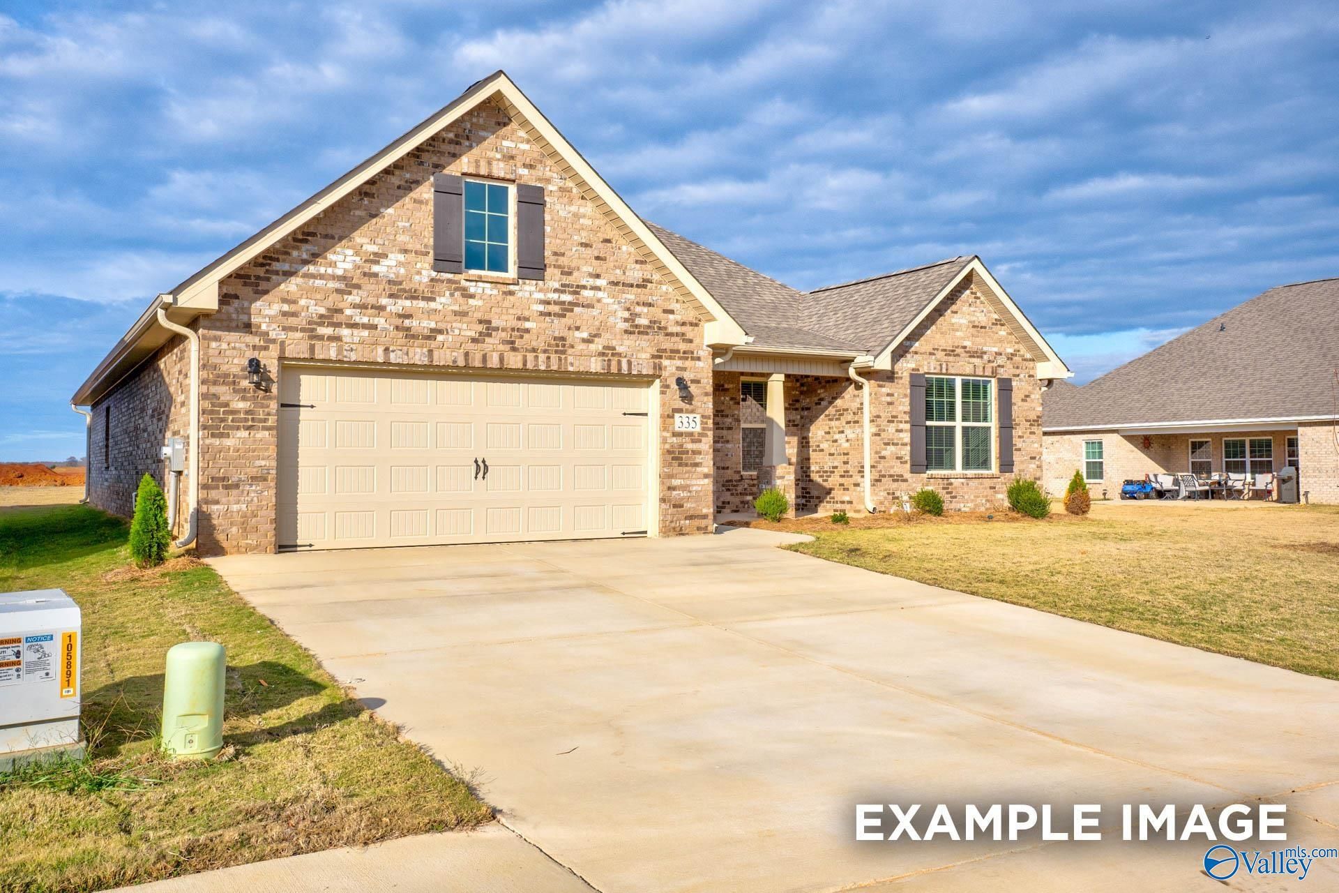 Brick 1-story Rockford floor plan home with 2-car garage, driveway, and shrubs in Creekside, Harvest, Alabama