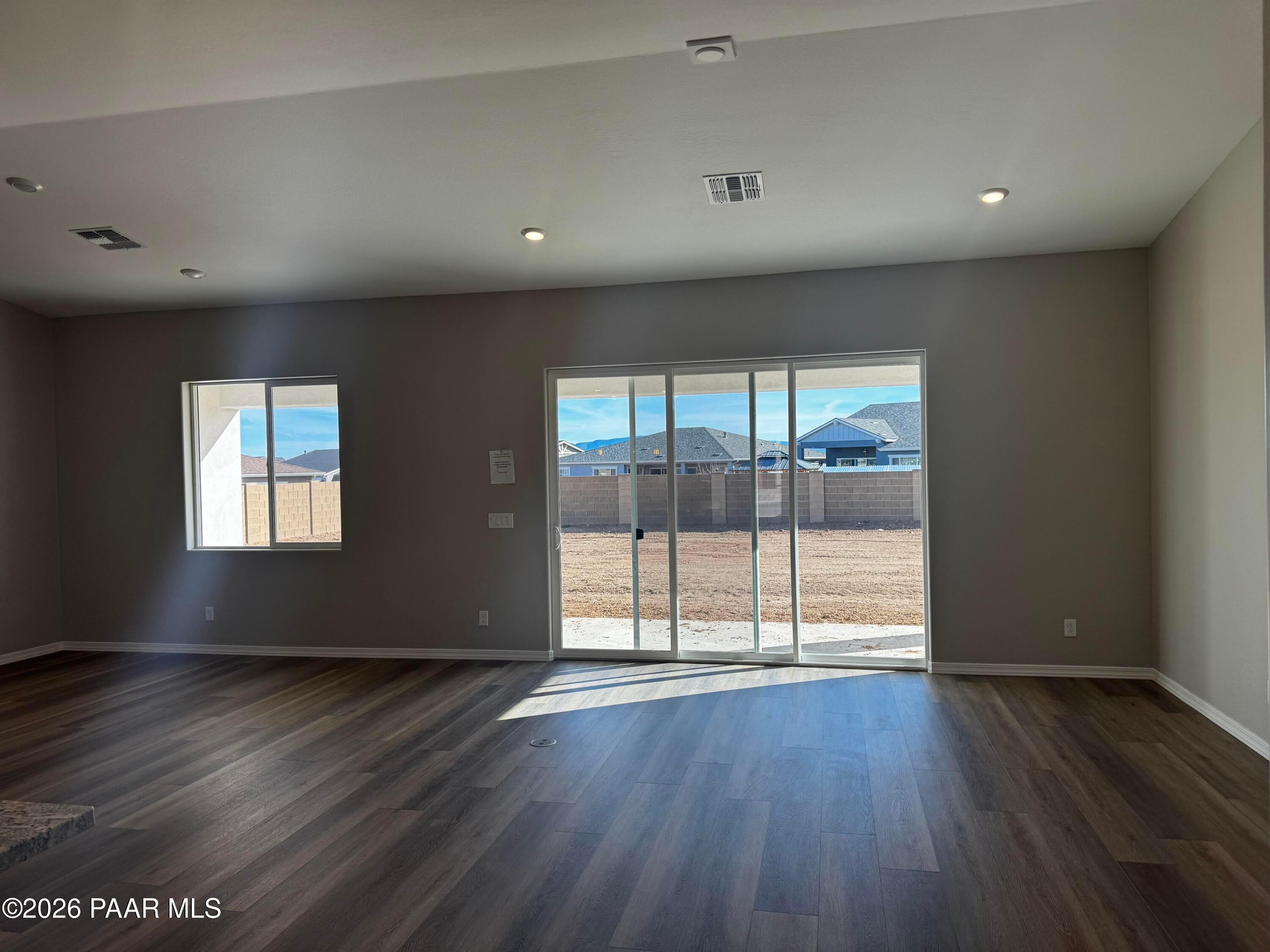 Bright empty living room with hardwood floors, sliding doors to desert backyard in Davidson Homes Daybreak B, Prescott AZ