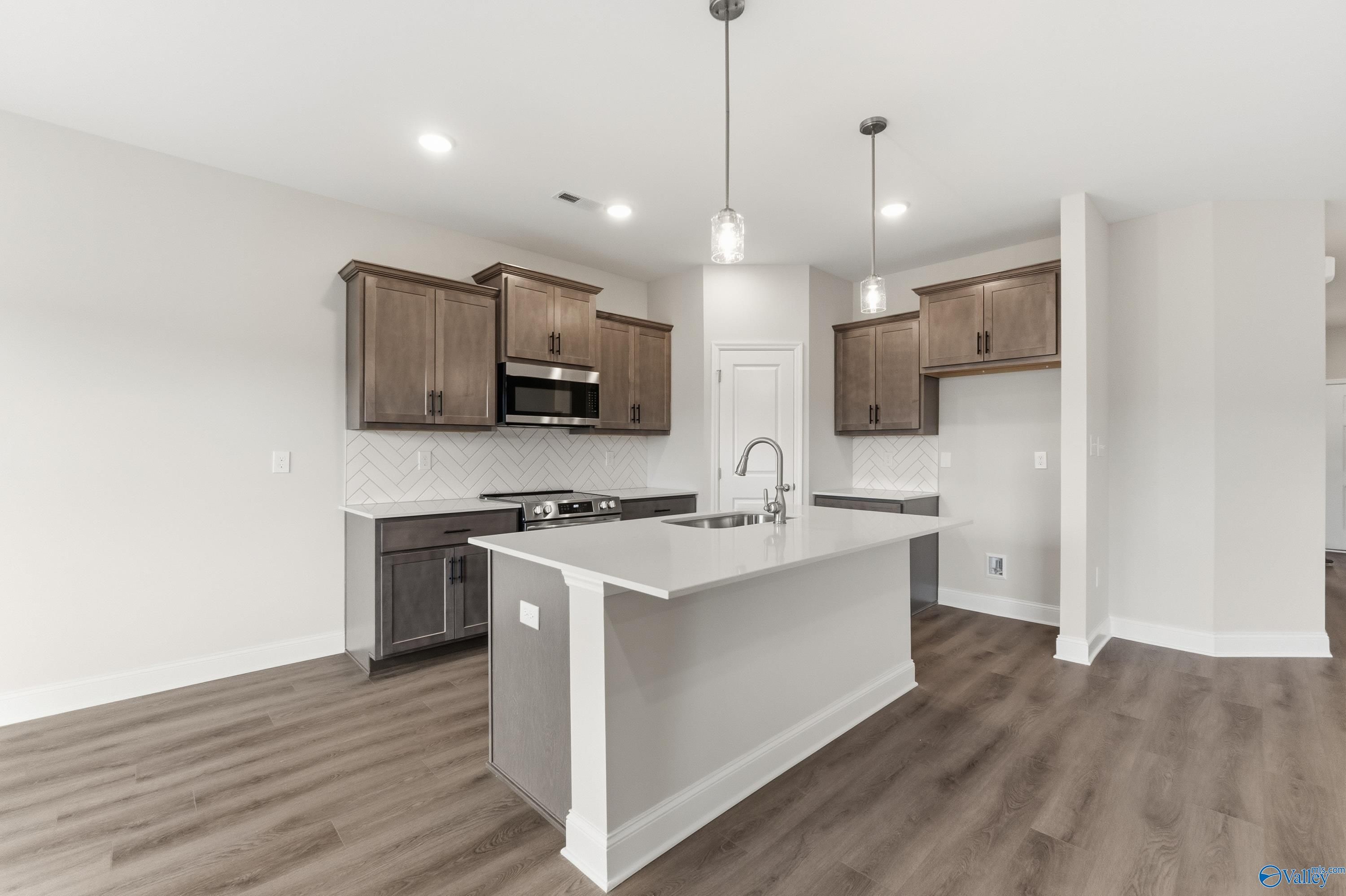 Modern kitchen featuring white quartz island, shaker cabinets, stainless steel appliances in The Asheville C, Huntsville AL