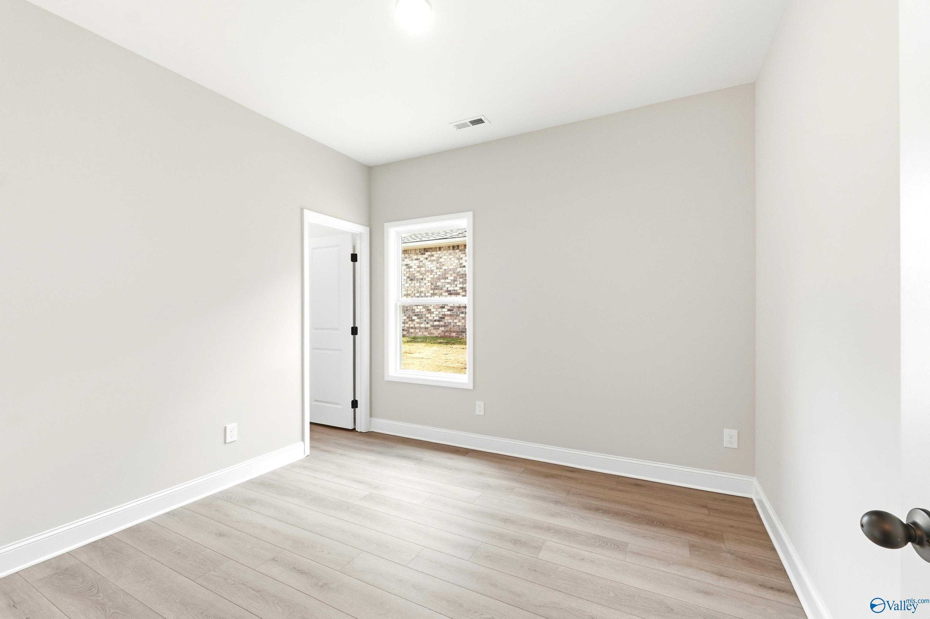 Bright, neutral-toned bedroom with wood-look flooring in The Daphne C floor plan at Flint Meadows, New Market, Alabama.