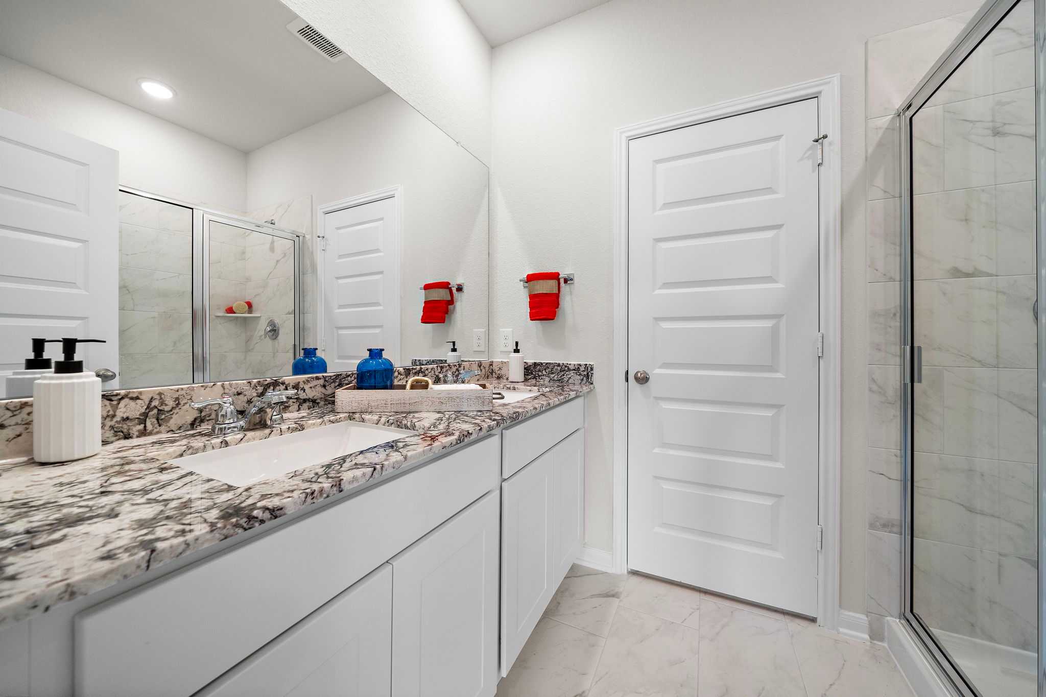 Modern bathroom with double vanity, marble countertop, walk-in glass shower at Liberty Estates in Cleveland TX by Davidson Homes
