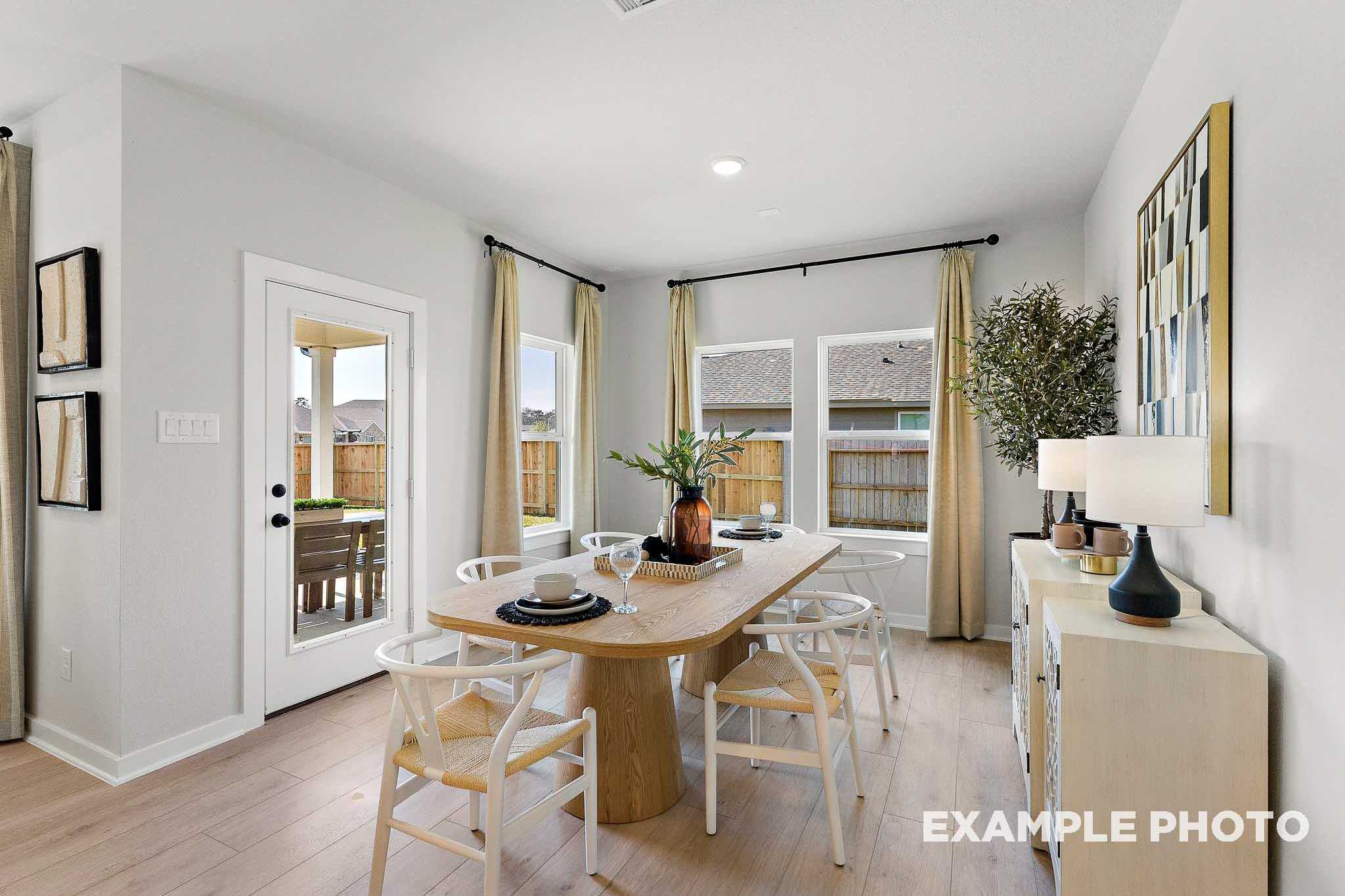 Modern dining room in The Everett E showcasing oak table, white chairs, French doors to backyard, and neutral decor