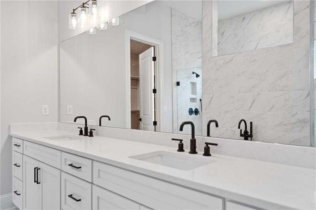 Elegant master bathroom double vanity with white cabinets, black faucets, subway tile, and glass shower in Davidson Homes The Seaside B, Woodstock, GA
