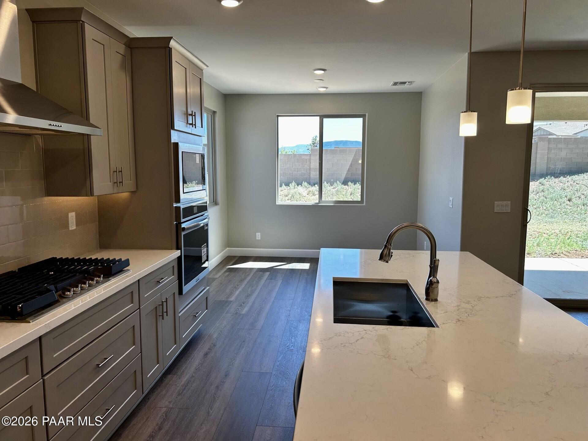 Modern kitchen with quartz island, stainless appliances, and wood-look flooring in The Harmony C at Pronghorn Ranch.