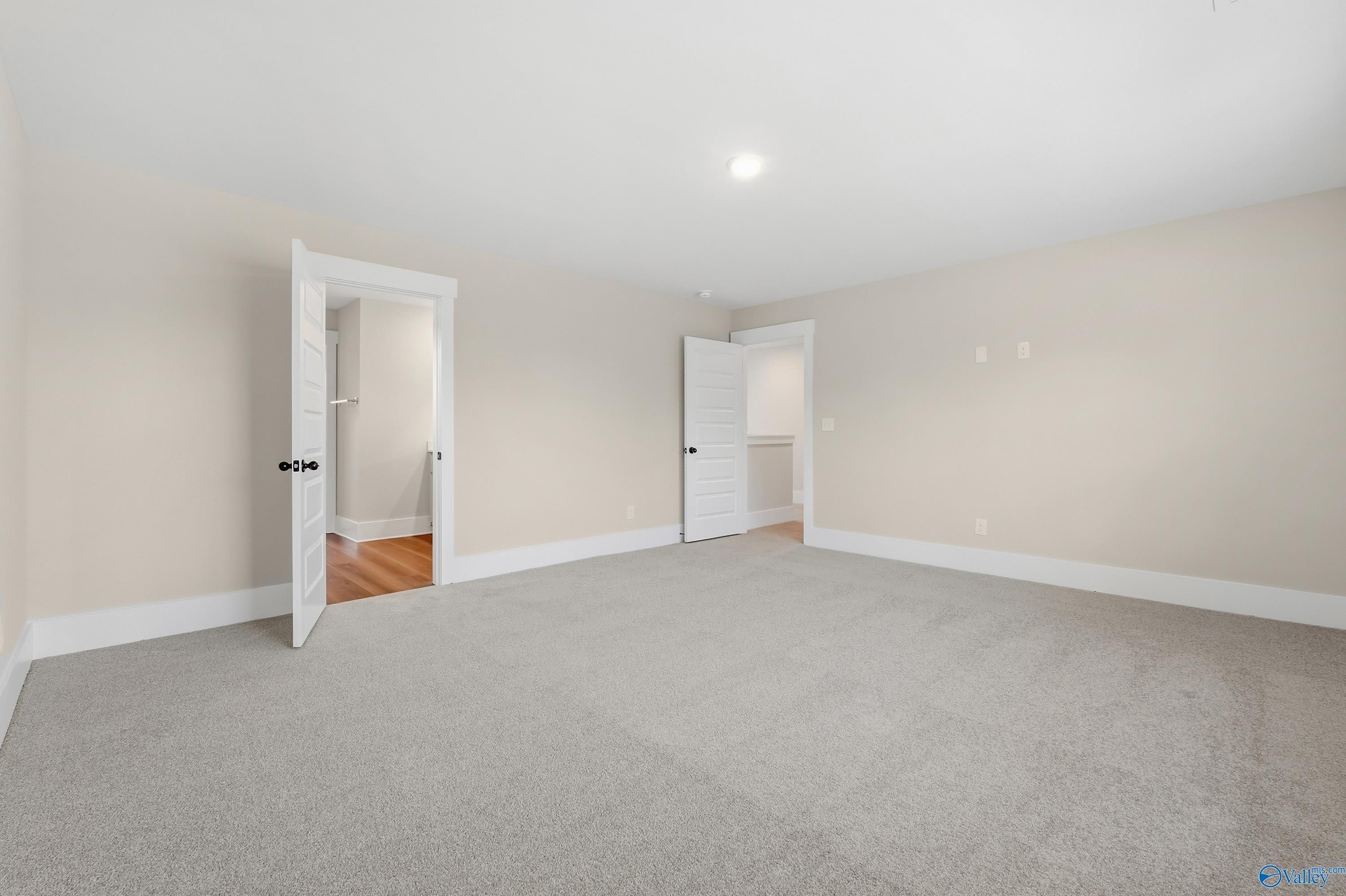 Spacious secondary bedroom with open door to private bath and hardwood foyer in Davidson Homes The Shelby A, Athens, Alabama