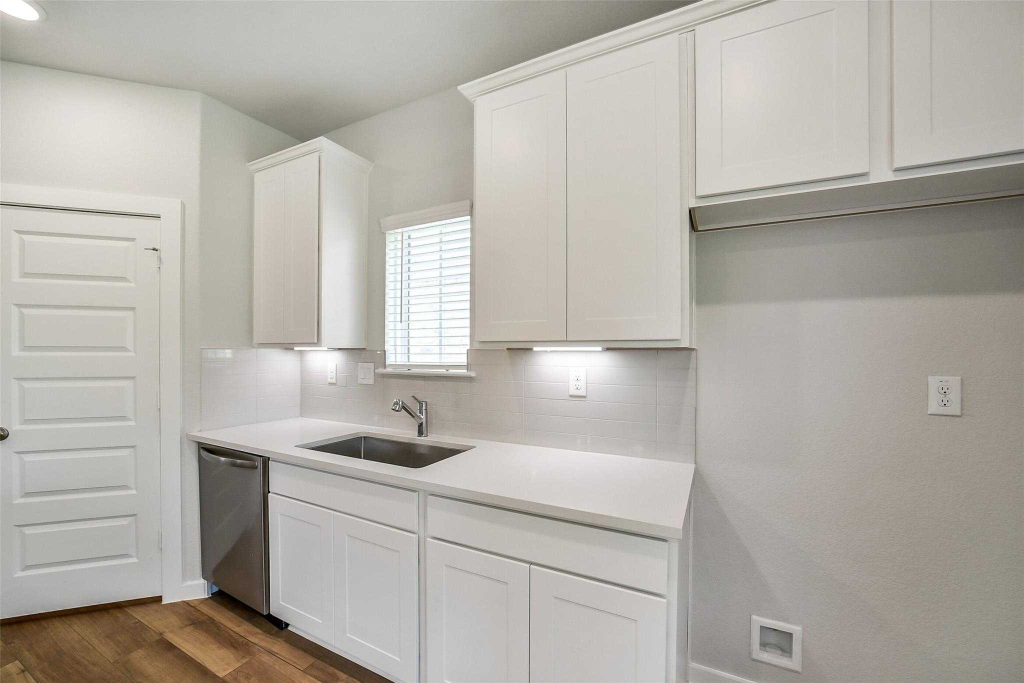 Bright white shaker kitchen with farmhouse sink, quartz counters, and subway tile in Davidson Homes The Trinity F, Magnolia Texas
