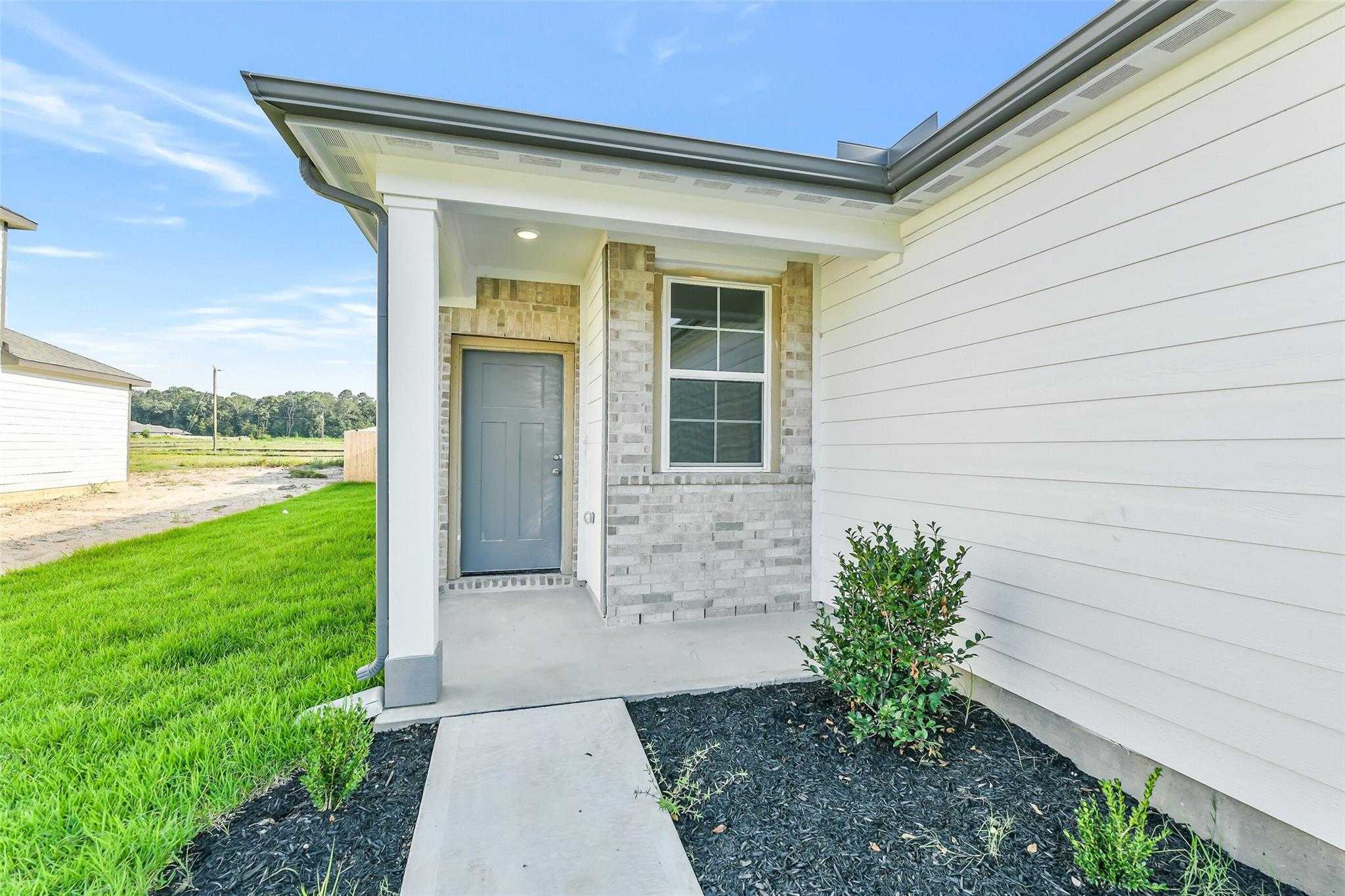 Modern front facade of Davidson Homes The Colorado F: white siding, brick accents, columned porch, gray door in Liberty Estates, Cleveland, Texas