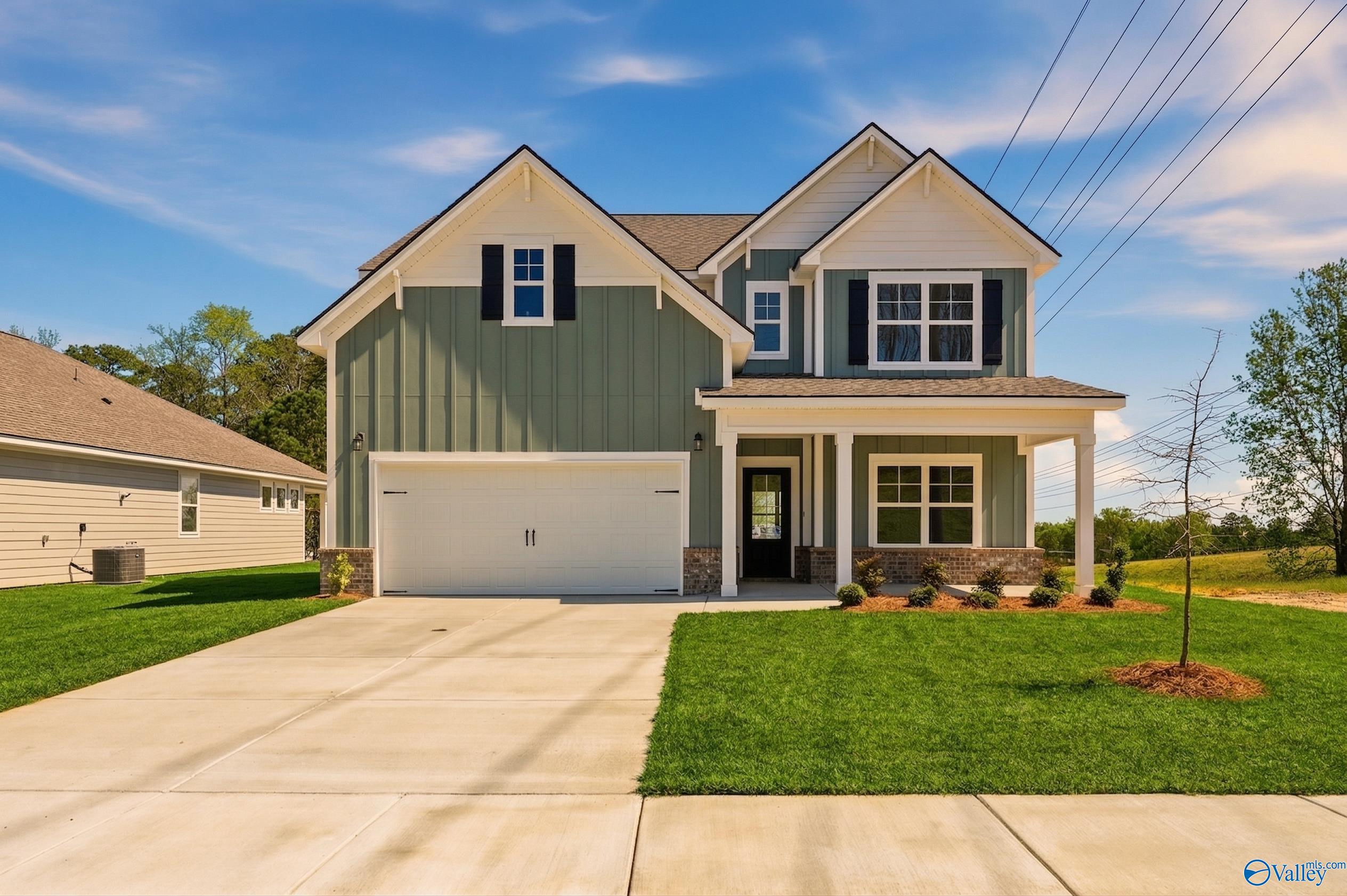 Modern two-story green-sided home with 2-car garage, covered porch, and manicured lawn in Noble Ridge, Cullman, Alabama