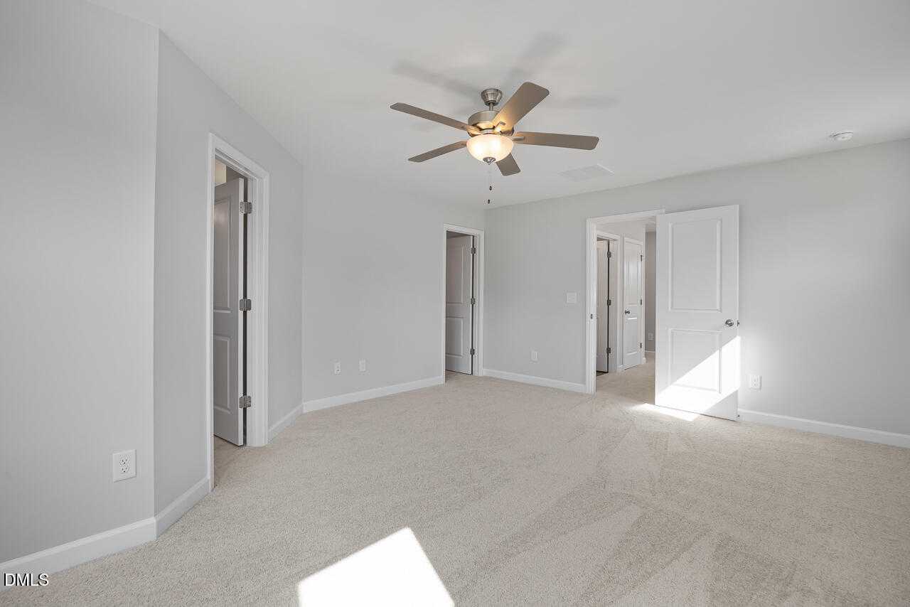 Bright upstairs hallway with ceiling fan, gray walls, carpet flooring, and adjacent bedrooms in Davidson Homes The Graham, Fuquay-Varina