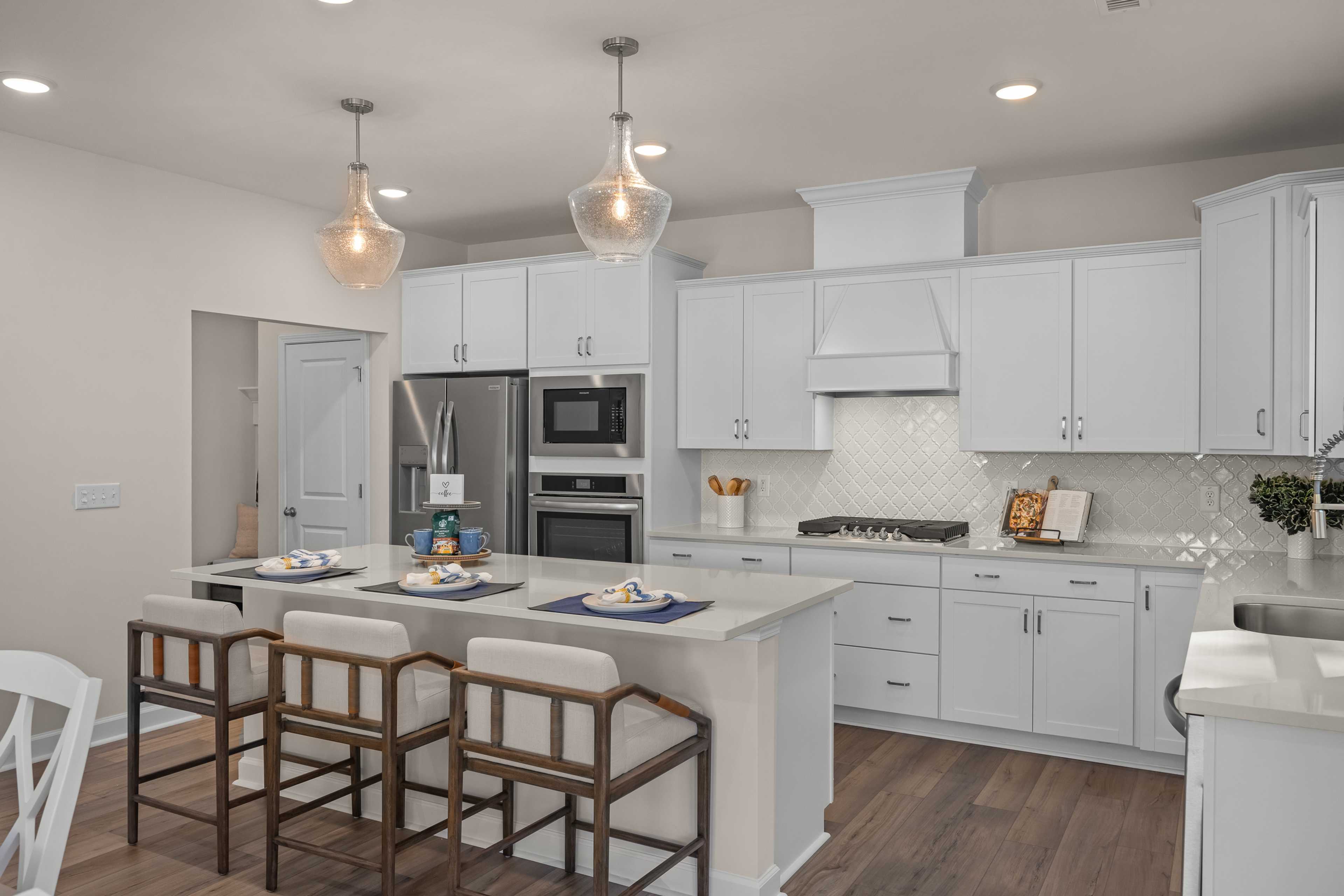 Spacious modern kitchen with white cabinets, large island seating, stainless appliances at Enclave at Belmont in Belmont NC