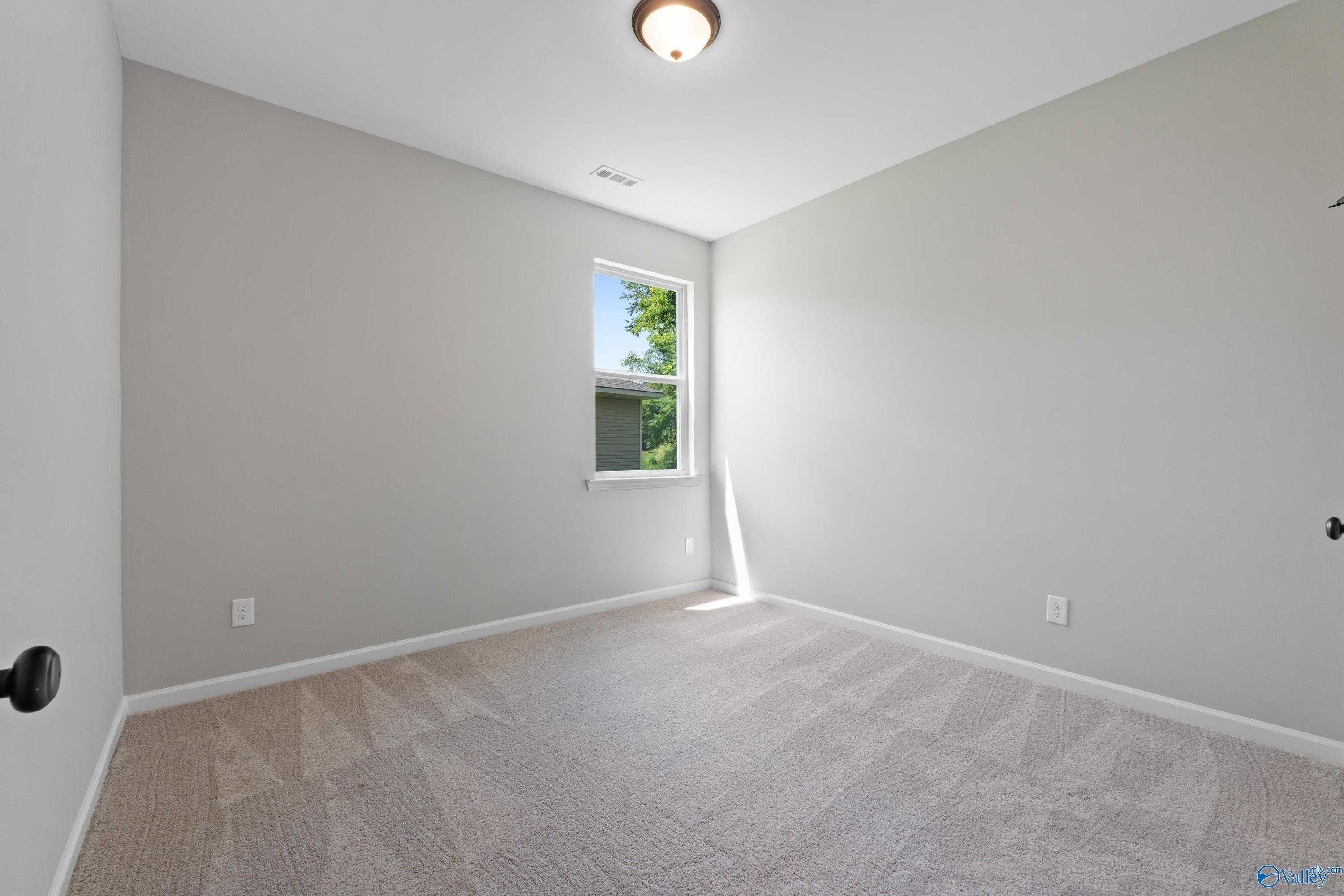 Bright secondary bedroom with gray walls, beige carpet, and large window in Davidson Homes The Phoenix, Hazel Green, AL