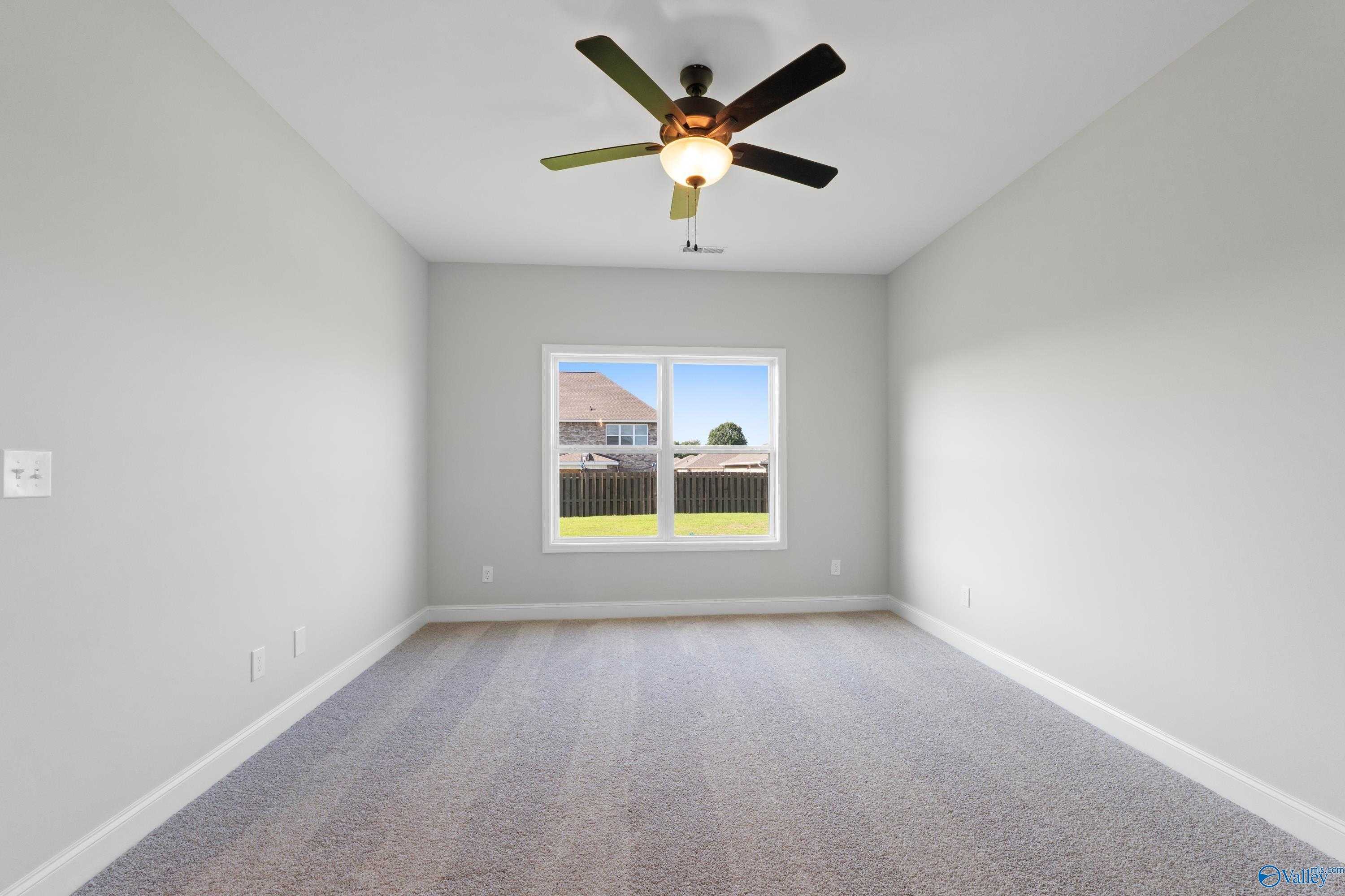 Spacious empty bedroom with ceiling fan and large window overlooking backyard in Davidson Homes The Franklin C, Hazel Green, Alabama
