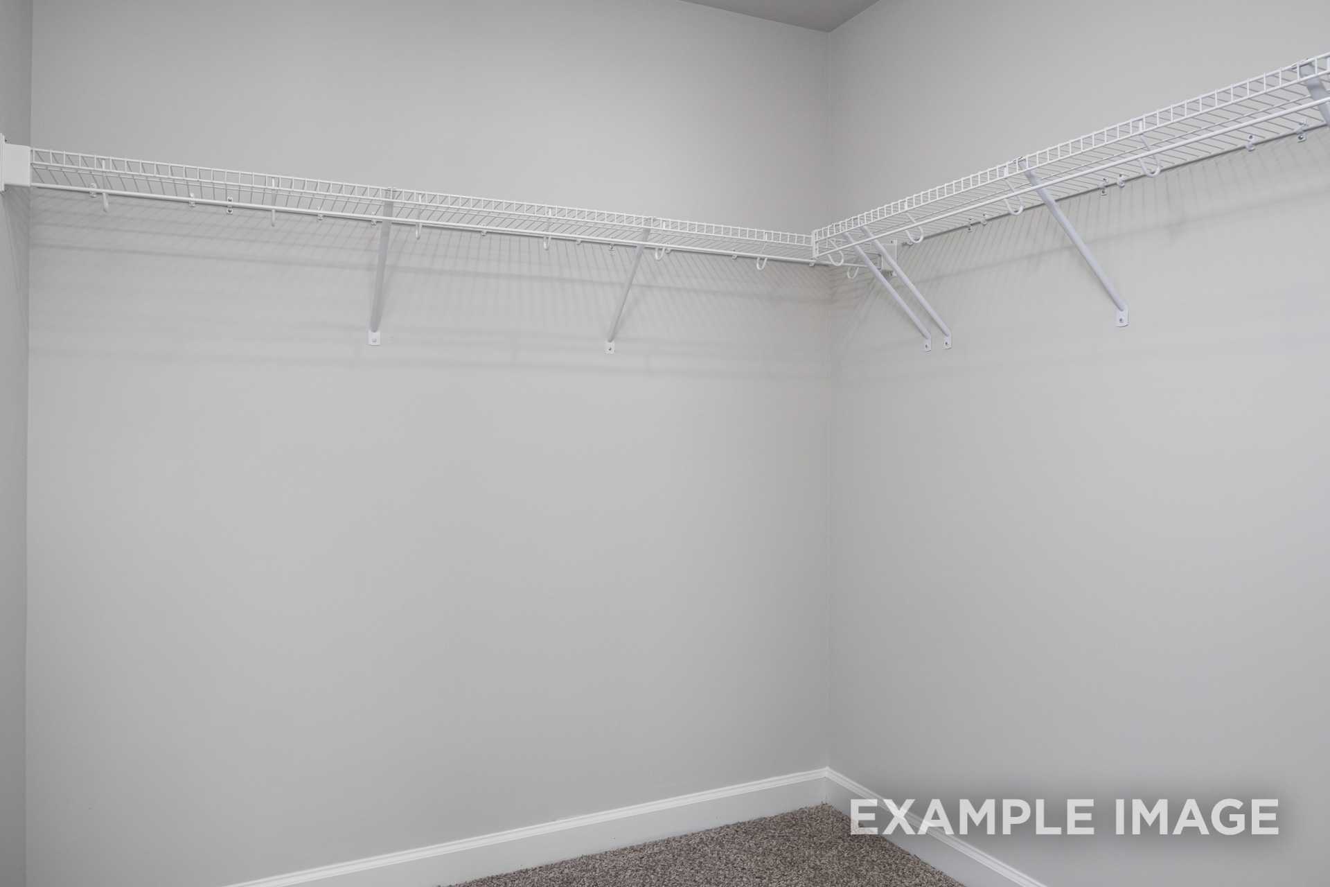 Spacious walk-in closet in The Preston B master suite featuring white wire shelving on light gray walls