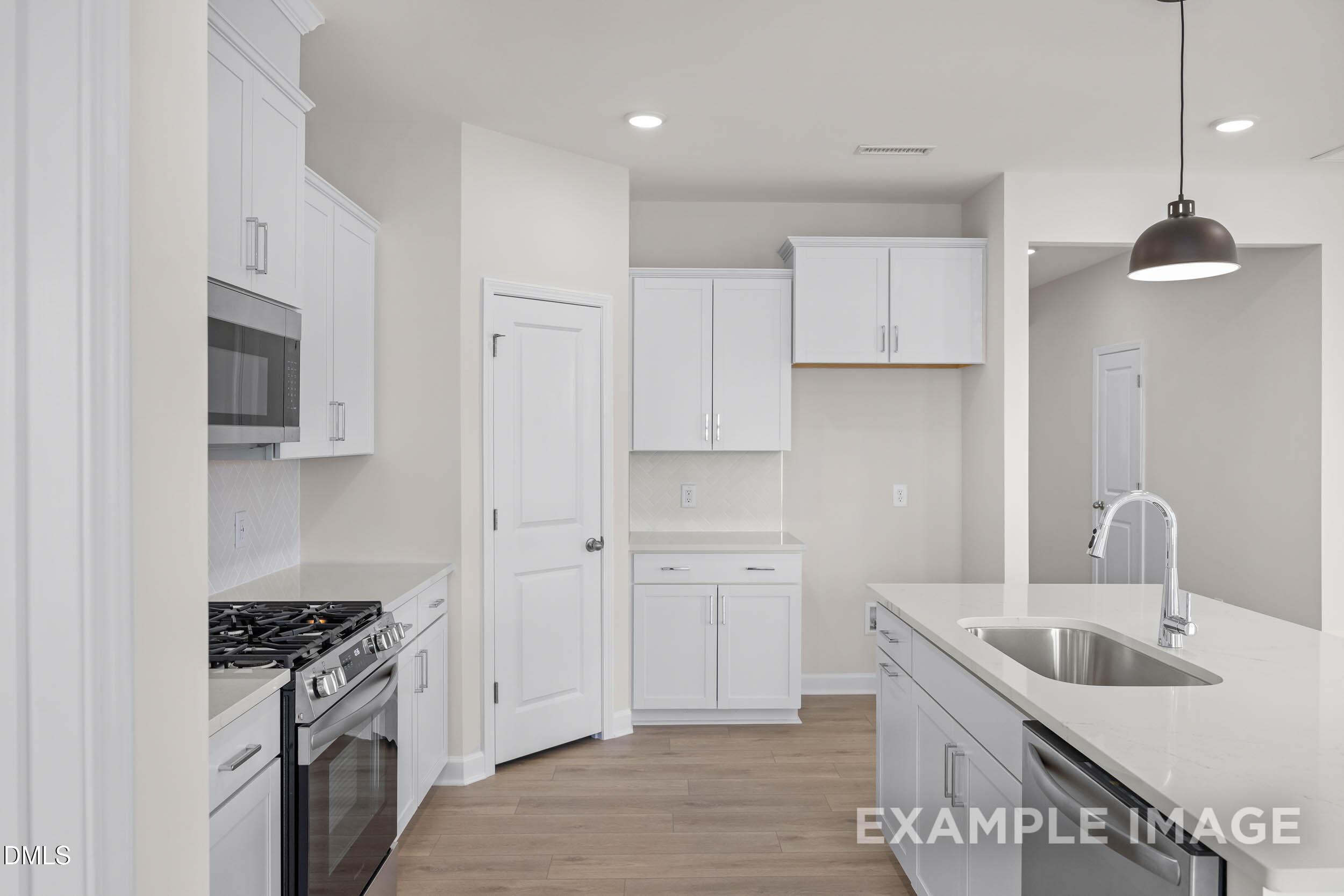 Modern kitchen with white cabinets, quartz countertops, and island in The Franklin C floor plan at Retreat at North Main.