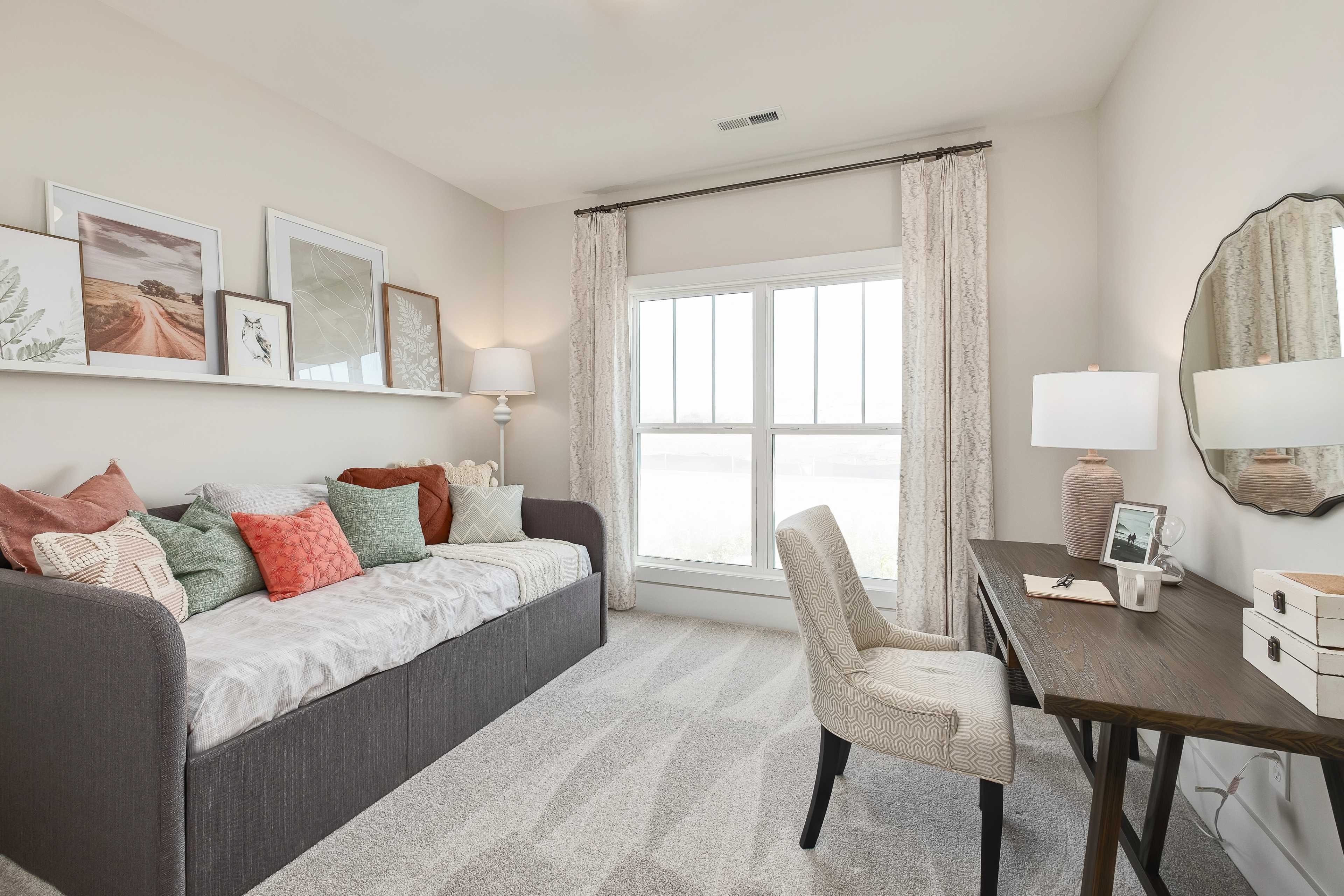 Cozy guest room at Mallard Landing in Athens Alabama with gray daybed, colorful pillows, wooden desk, and large window