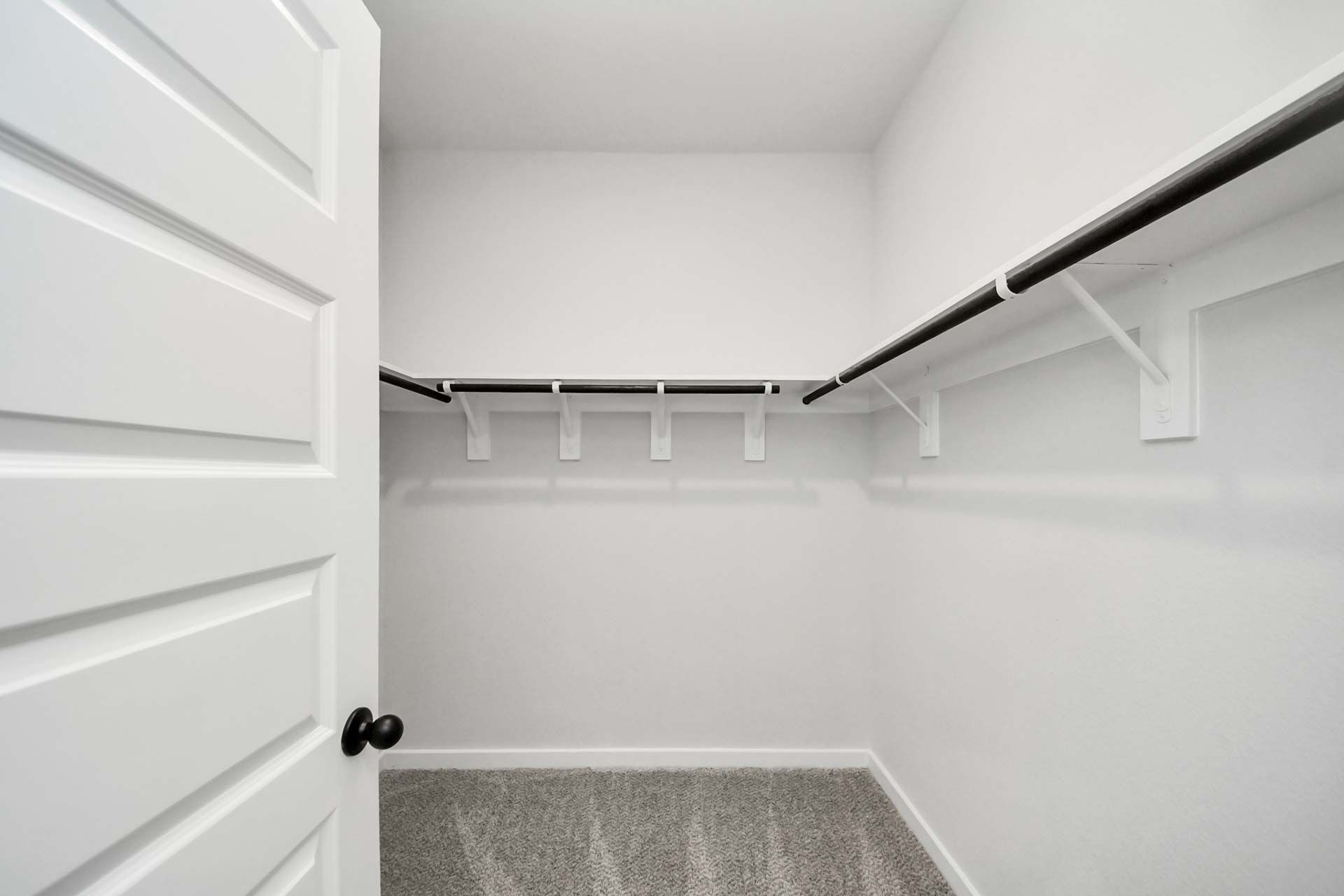 Walk-in closet with shelving and hanging rods at Enclave at Newport in Crosby, Texas by Davidson Homes.