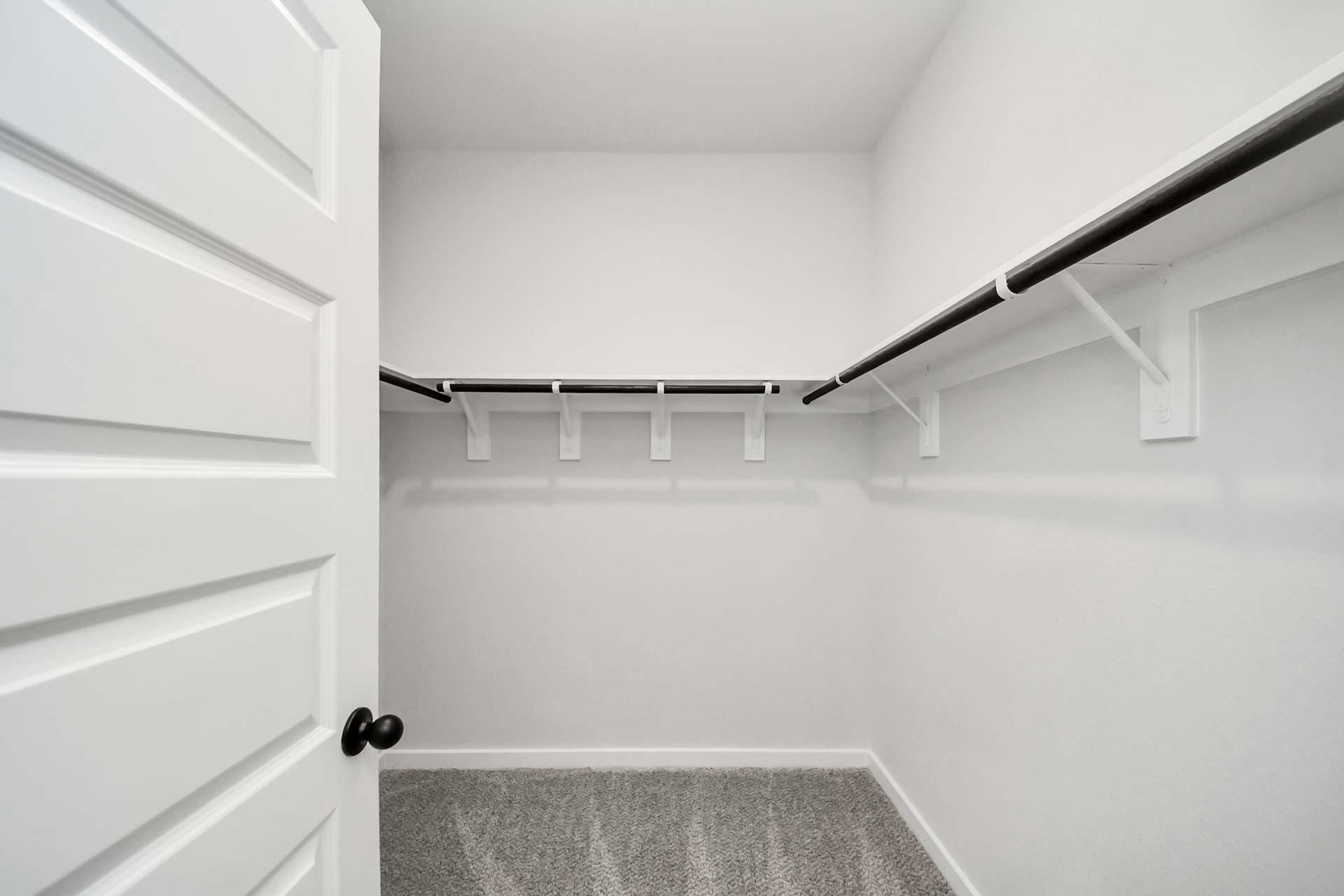 Walk-in closet with shelving and hanging rods at Enclave at Newport in Crosby, Texas by Davidson Homes.