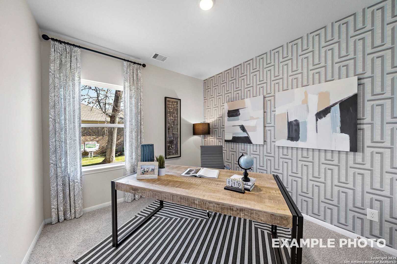Modern home office with rustic wooden desk, globe, abstract art, and geometric wallpaper in Davidson Homes The San Marcos D, San Antonio