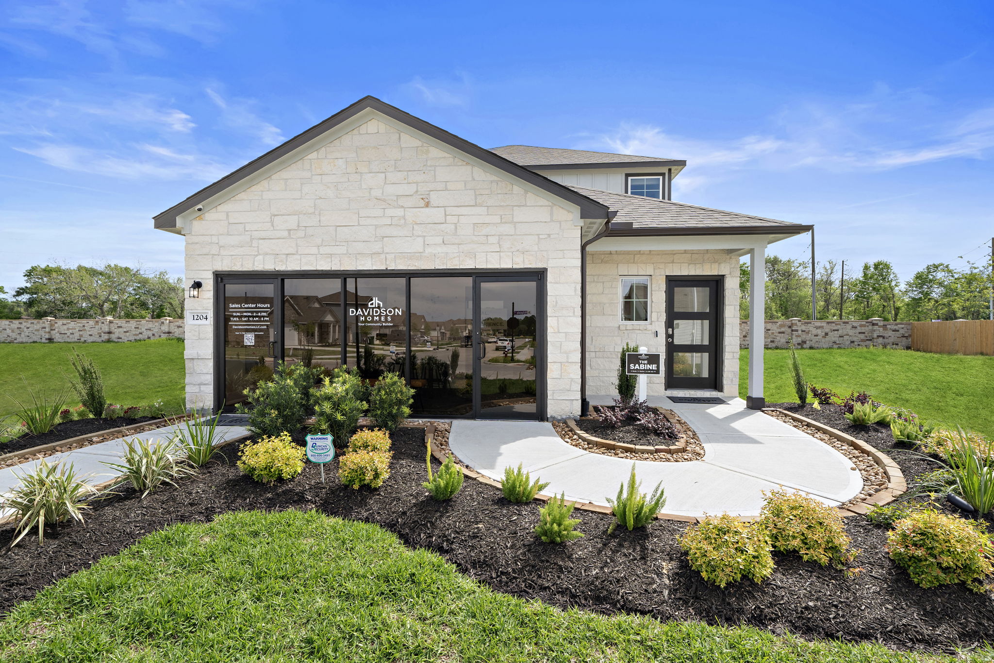 Davidson Homes sales center at The Villages at WestPointe in Dayton, Texas featuring stone exterior and landscaping.