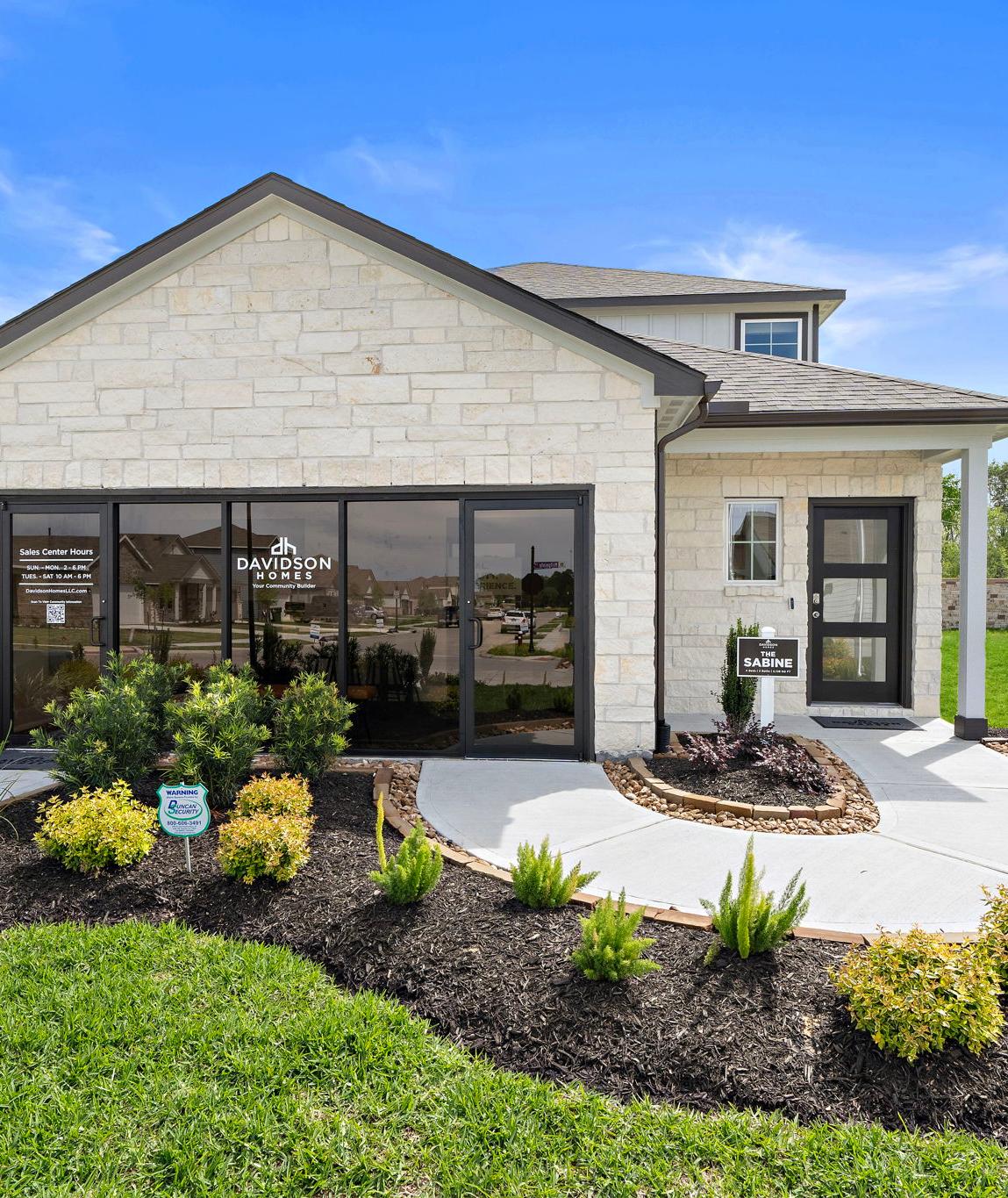 Davidson Homes sales center at The Villages at WestPointe in Dayton, Texas featuring stone exterior and landscaping.