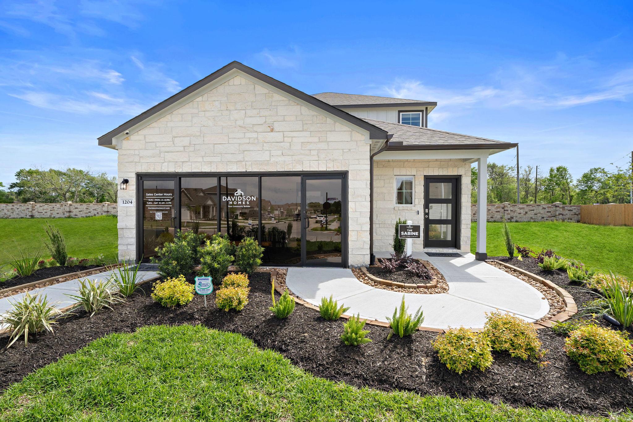 Davidson Homes sales center at The Villages at WestPointe in Dayton, Texas featuring stone exterior and landscaping.