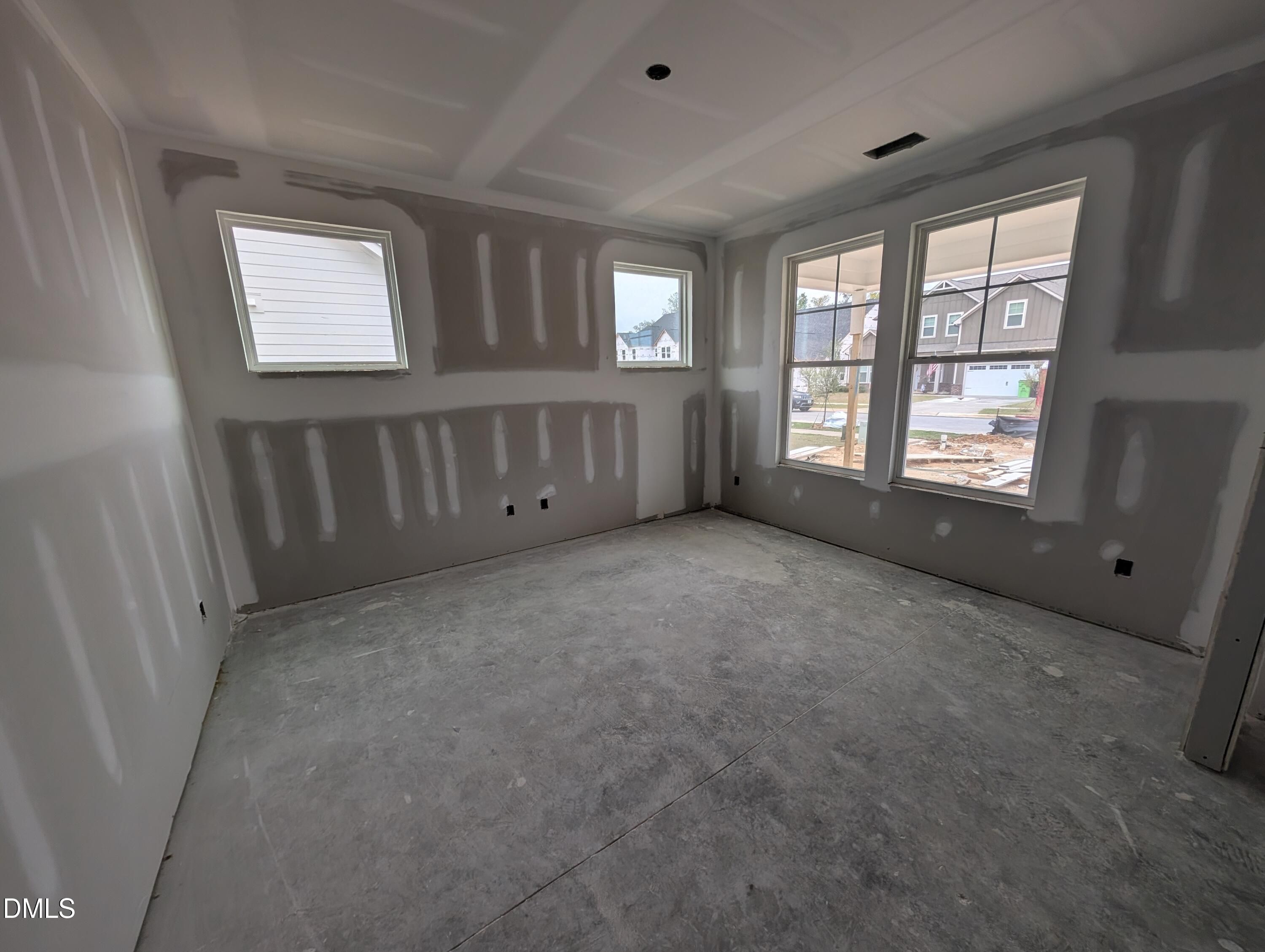 Unfinished room with taped drywall, coffered ceiling, and large windows in Davidson Homes The Aspen C, Wendell Ridge, North Carolina