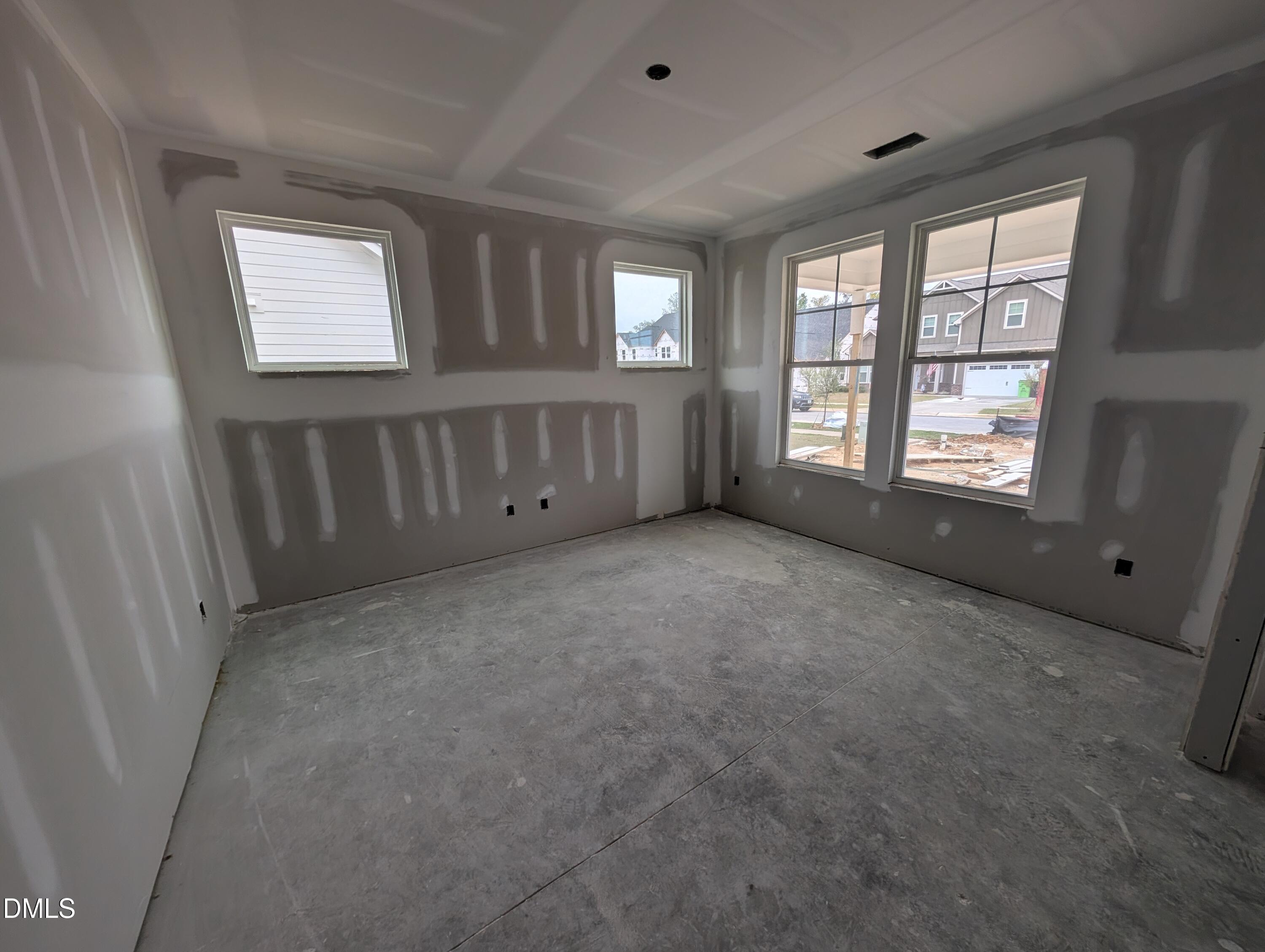 Unfinished room with taped drywall, coffered ceiling, and large windows in Davidson Homes The Aspen C, Wendell Ridge, North Carolina