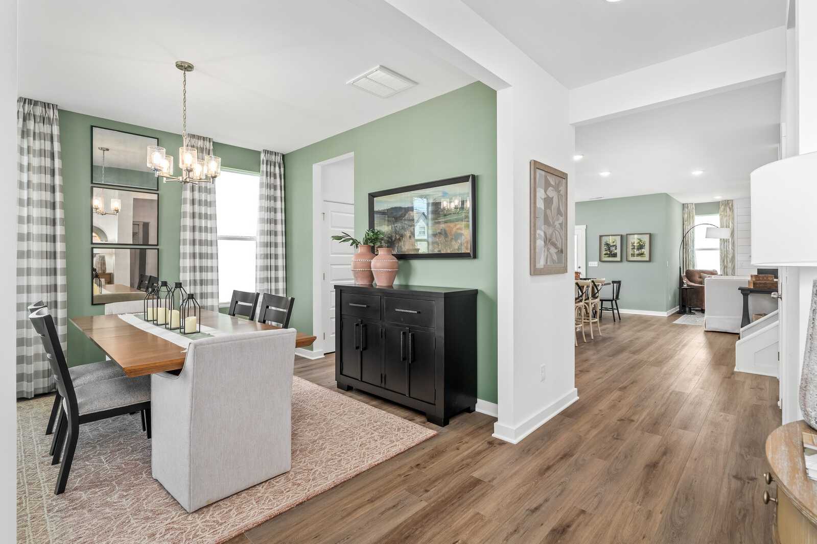 Spacious dining room in Calista Farms home, White House TN with green walls, chandelier, credenza, and open hardwood floor layout