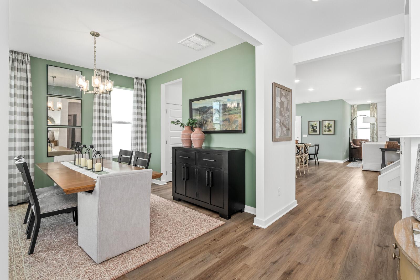 Spacious dining room in Calista Farms home, White House TN with green walls, chandelier, credenza, and open hardwood floor layout