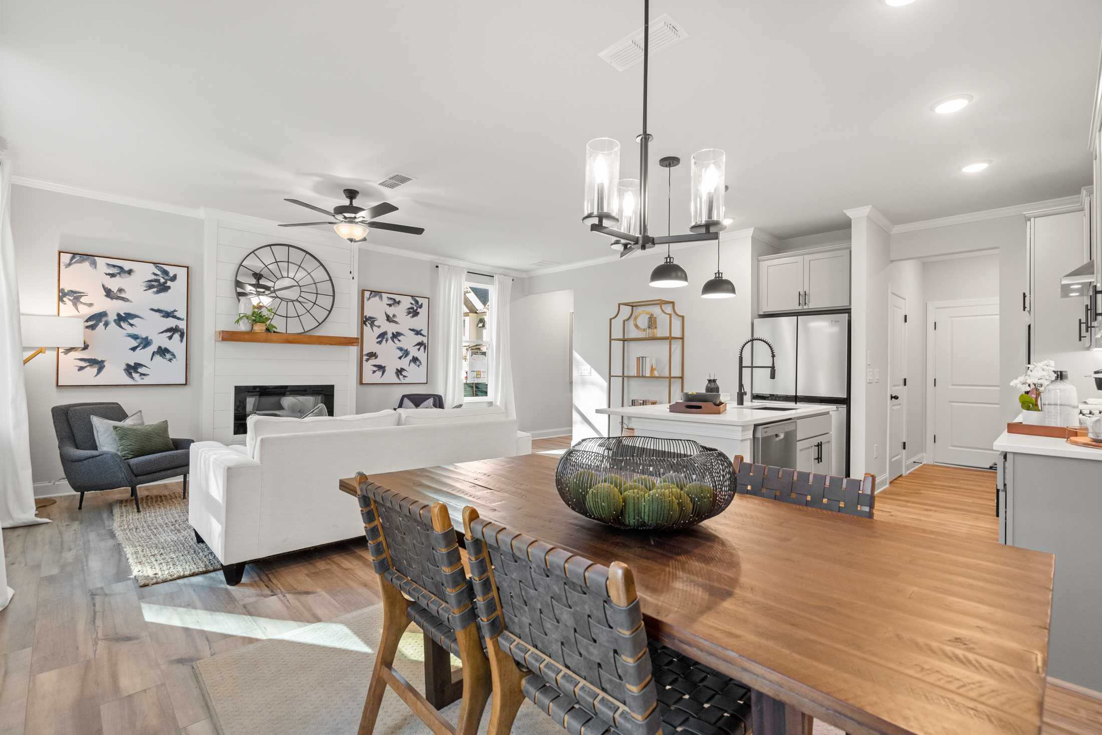 Open-concept living room and kitchen at Rosehill Townhomes in Marietta GA with hardwood floors, fireplace, and pendant lights