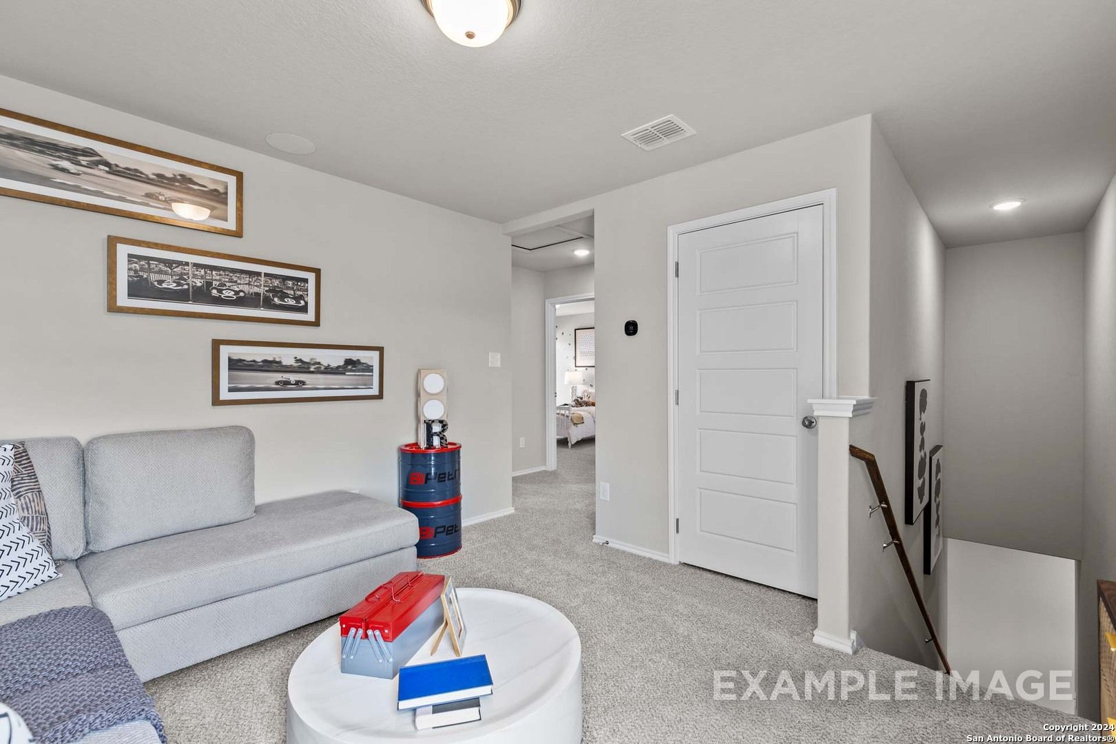 Cozy upstairs loft with gray sofa, round coffee table, framed artwork, and adjacent bedroom in 4-bed Sabine B home, Applewhite Meadows, San Antonio