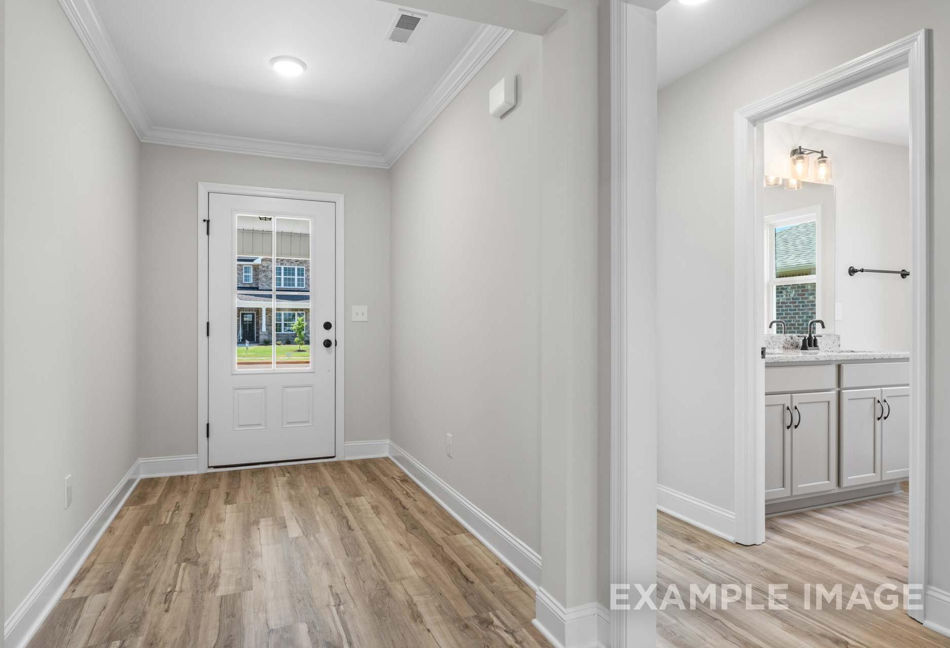 Spacious entry hall and laundry room in The Holly home design, light gray walls, hardwood floors, white glass door, sink cabinet