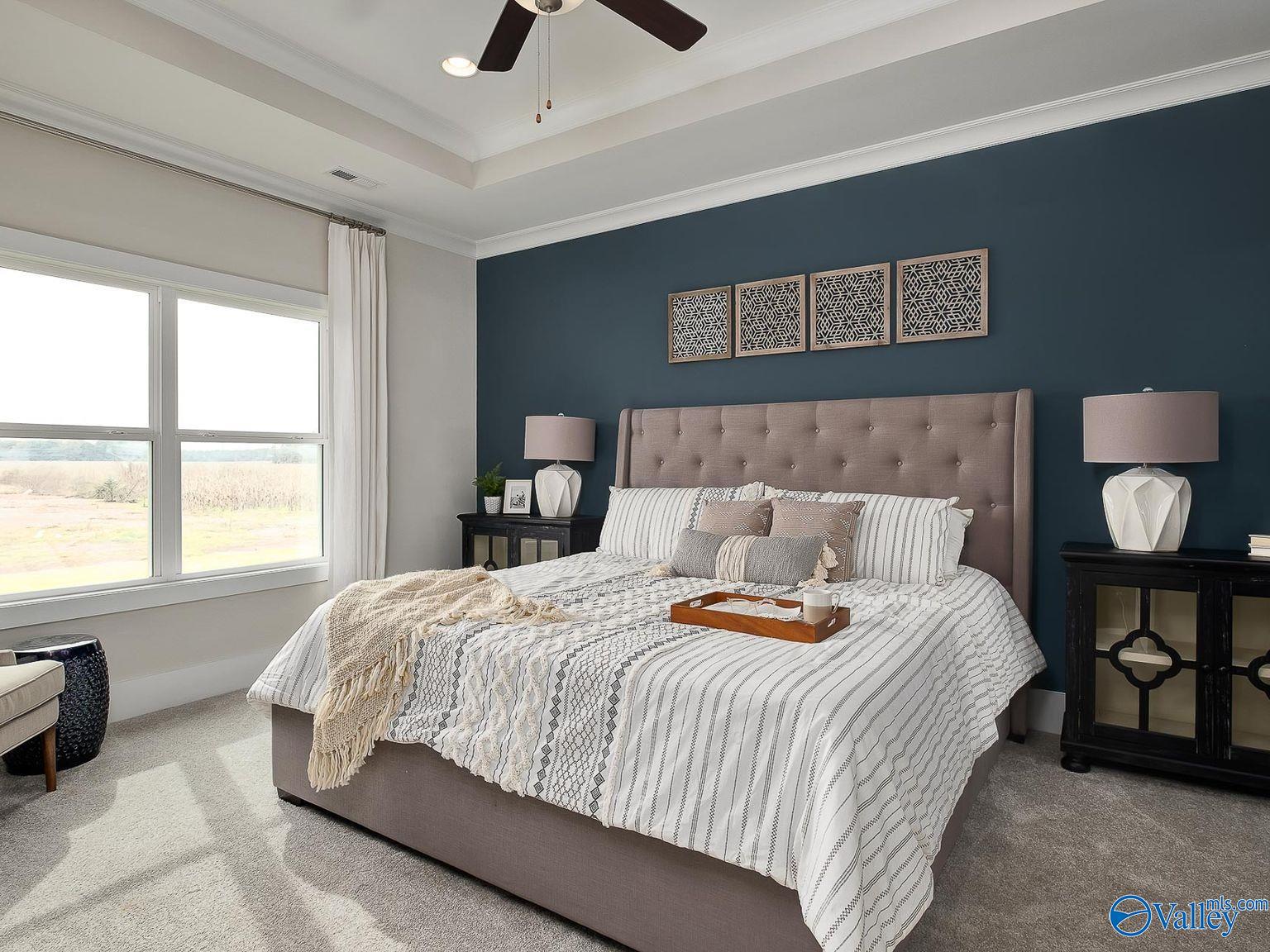 Elegant master bedroom with navy accent wall, tray ceiling fan, and scenic views in Davidson Homes The Everett, Toney, Alabama