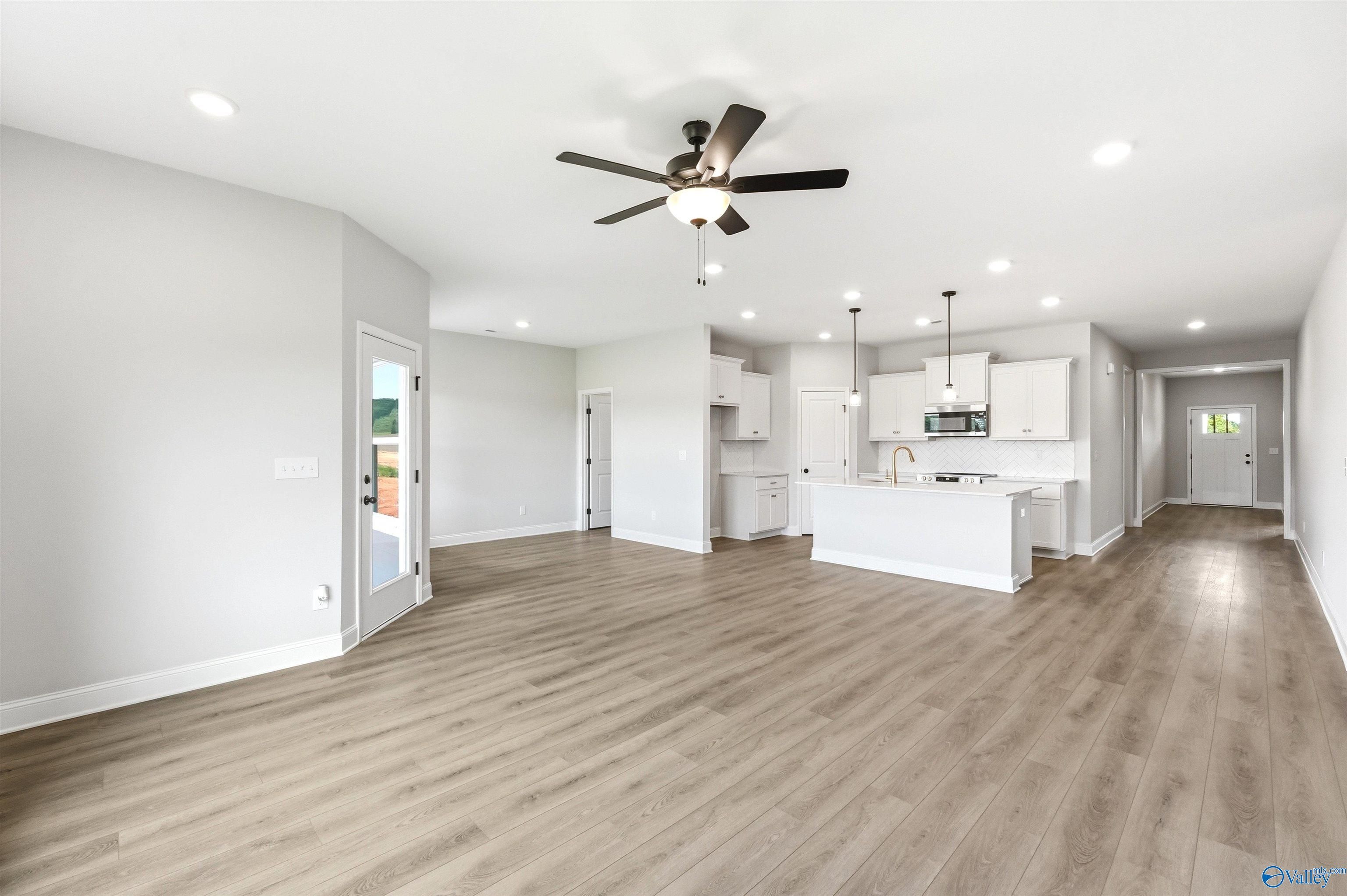 Open-concept living room and kitchen with wood-look flooring in The Daphne F floor plan at Berry Cove, New Market, AL.