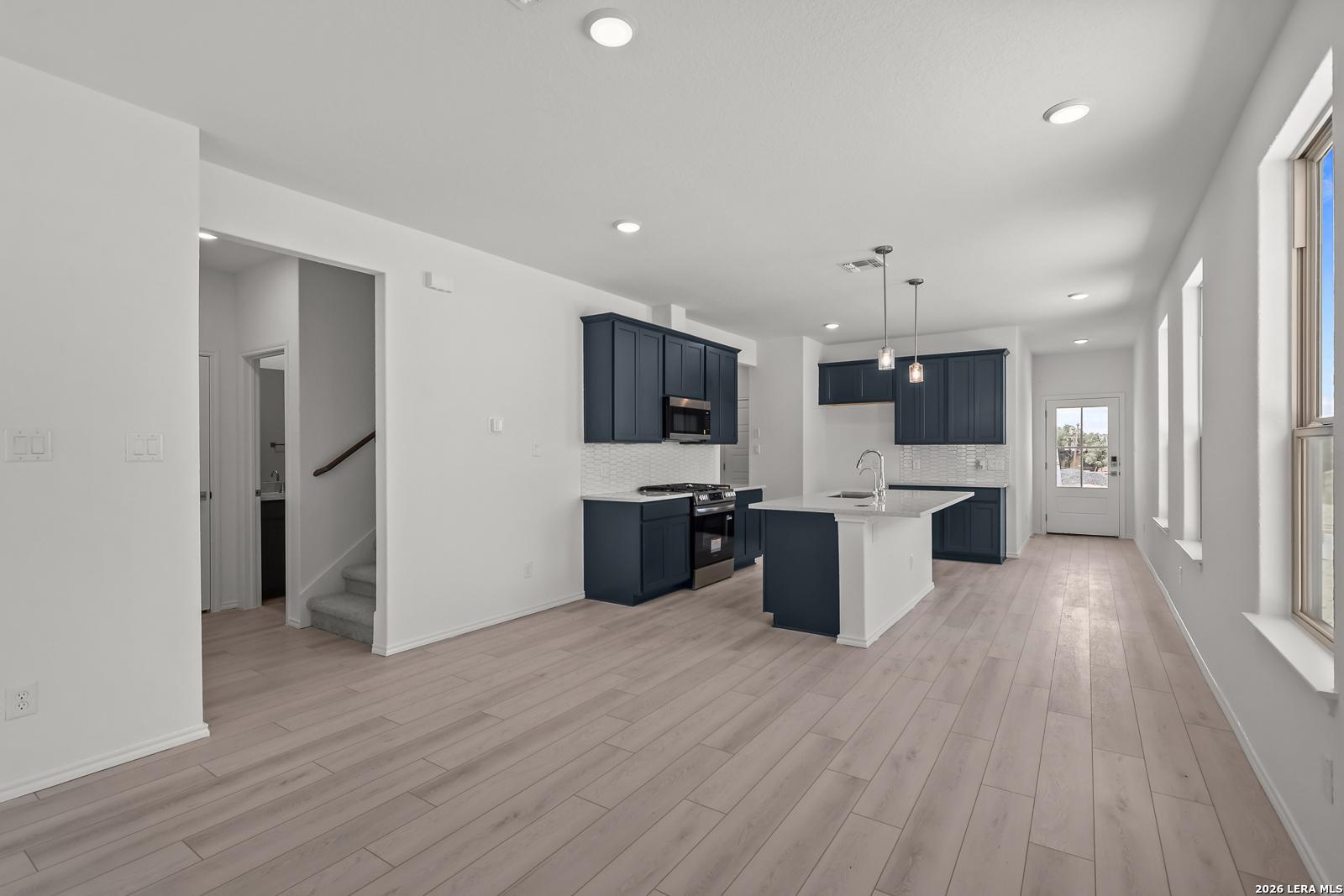Modern kitchen with navy cabinets and white island in The Gillian C floor plan at Meadows at Oak Creek, San Antonio, Texas.