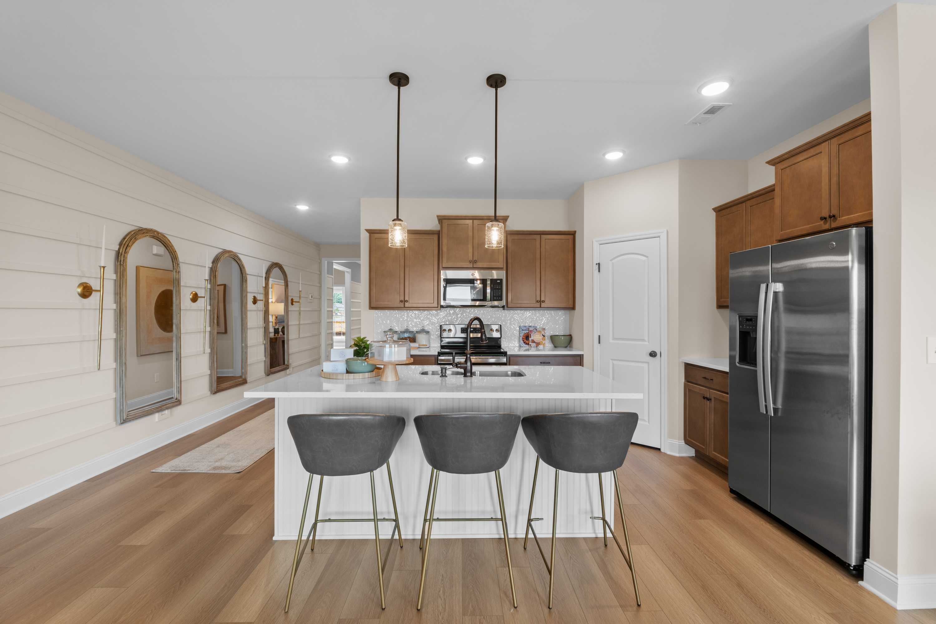 Modern open-concept kitchen in The Daphne F with white shiplap walls, large island, bar stools, and stainless steel appliances