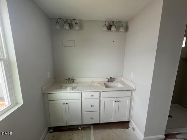 Modern double vanity bathroom with white shaker cabinets, sconce lights, and adjacent shower in Davidson Homes Adalynn B, Lillington, NC
