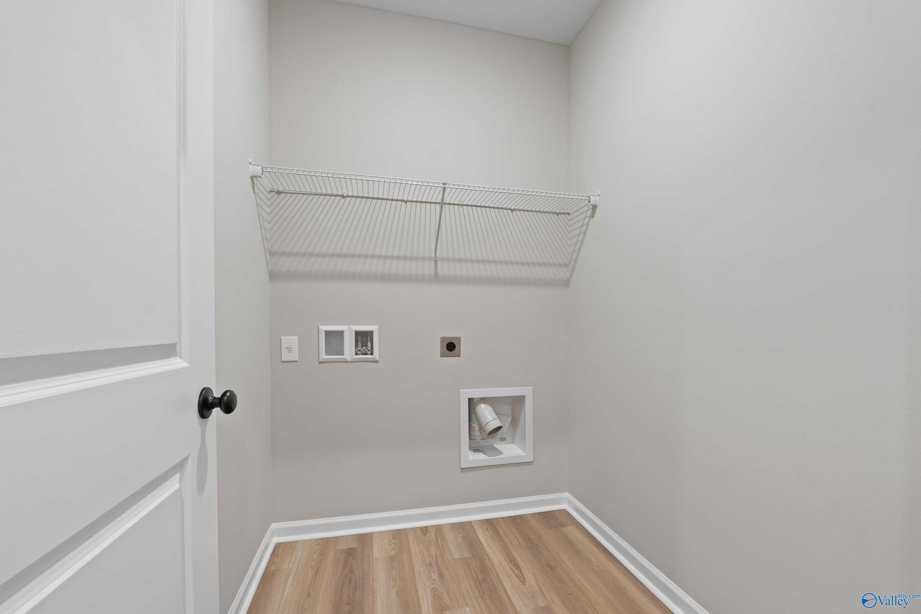 Spacious laundry room with wire shelving, washer/dryer hookups, and hardwood-look floors in Evermore Homes The Nantucket, Madison, Alabama