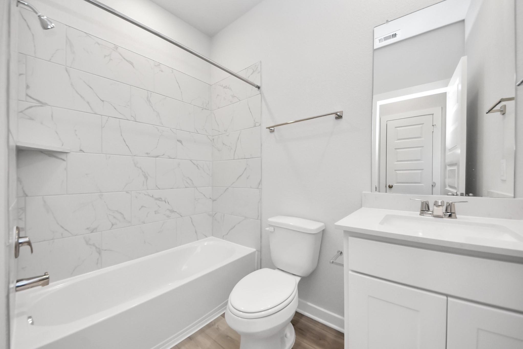 Modern bathroom with marble-style tile shower surround and white vanity in The Sabine E home at Windmill Estates, Magnolia.