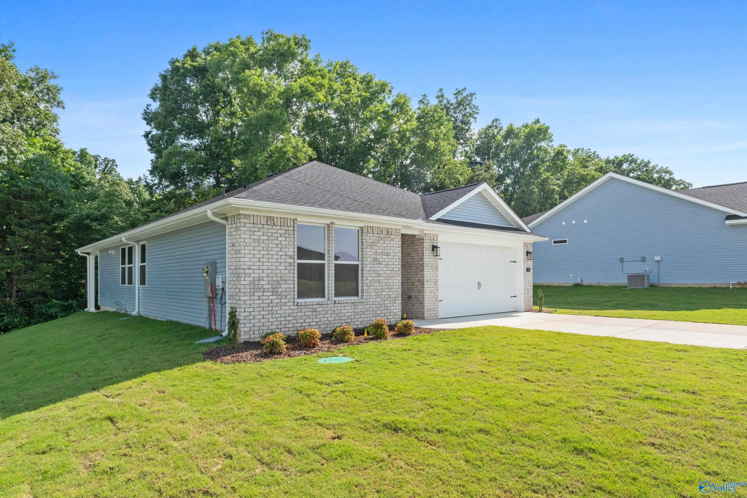 Single-story 3-bedroom Davidson Homes Polaris with blue siding, brick accents, 2-car garage, lush lawn in Bailey Park, Fayetteville, Tennessee