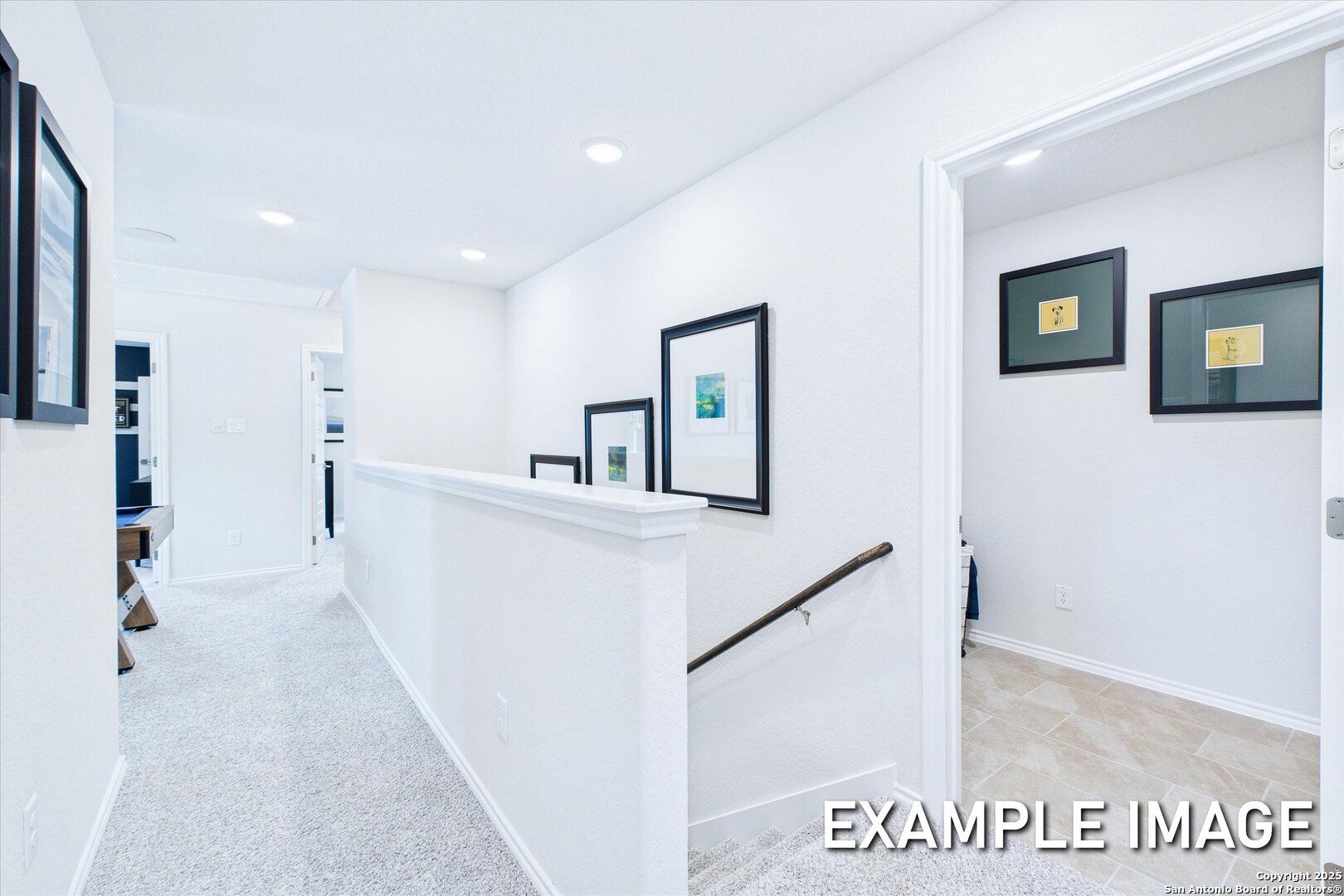 Bright upstairs hallway with white balustrade, recessed lights, and framed art overlooking staircase in Davidson Homes The Gillian B, San Antonio